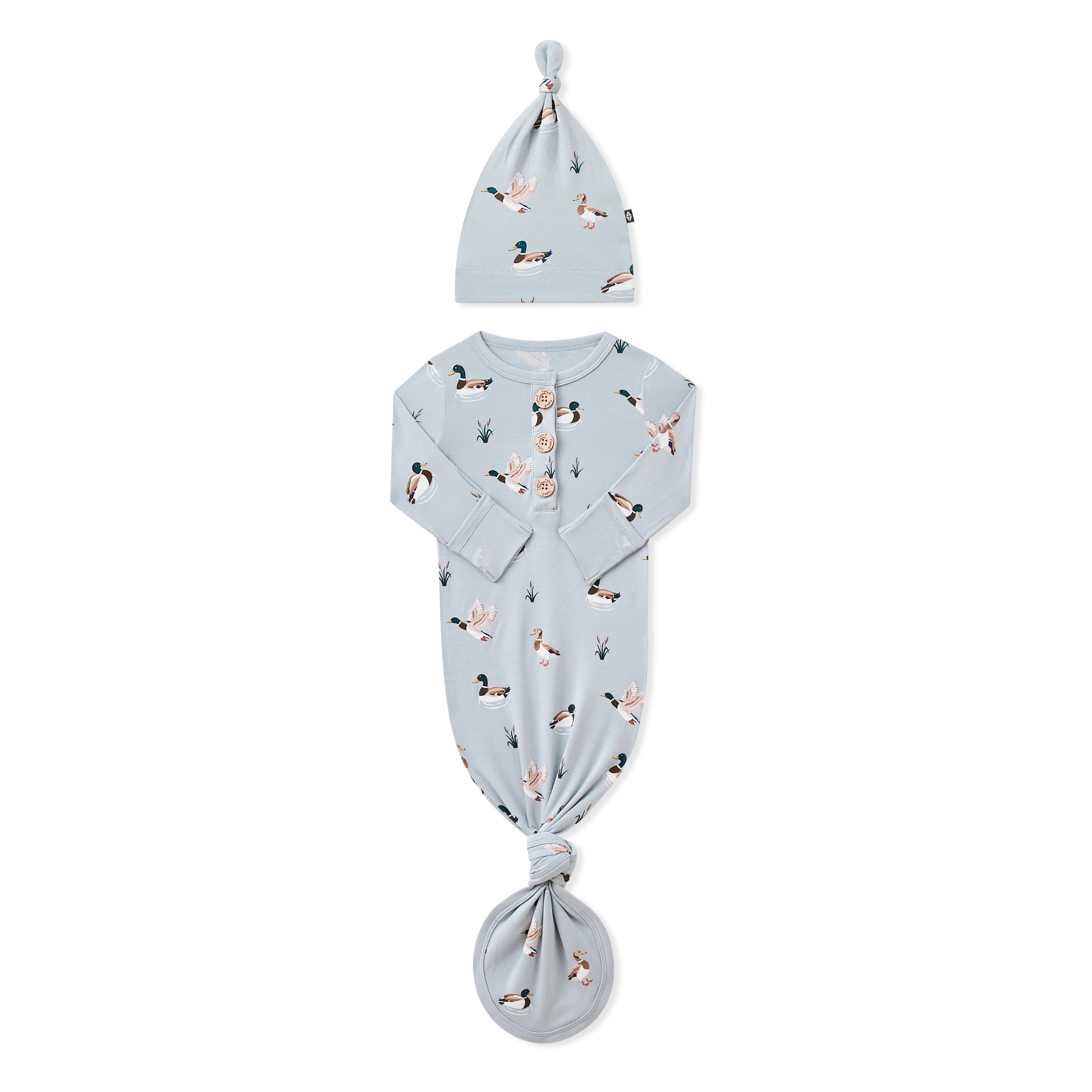 Knotted Gown with Hat Set in Mallard Duck with the arms folded inward laying on a white surface