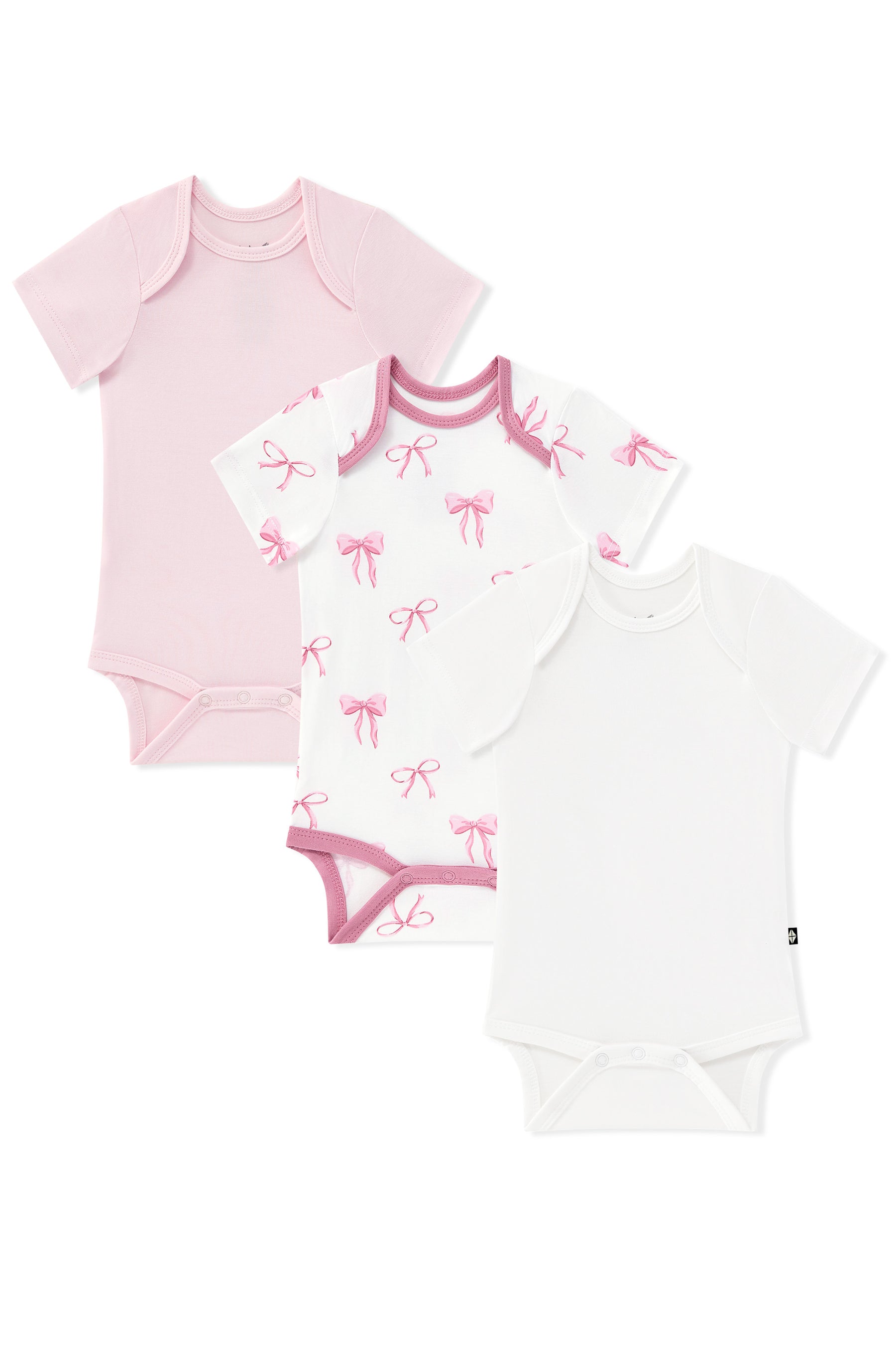 Three short-sleeve baby bodysuits arranged in an overlapping flat lay on a white background: a solid light pink one, a white one with pink bow prints and pink trim, and a solid white one.