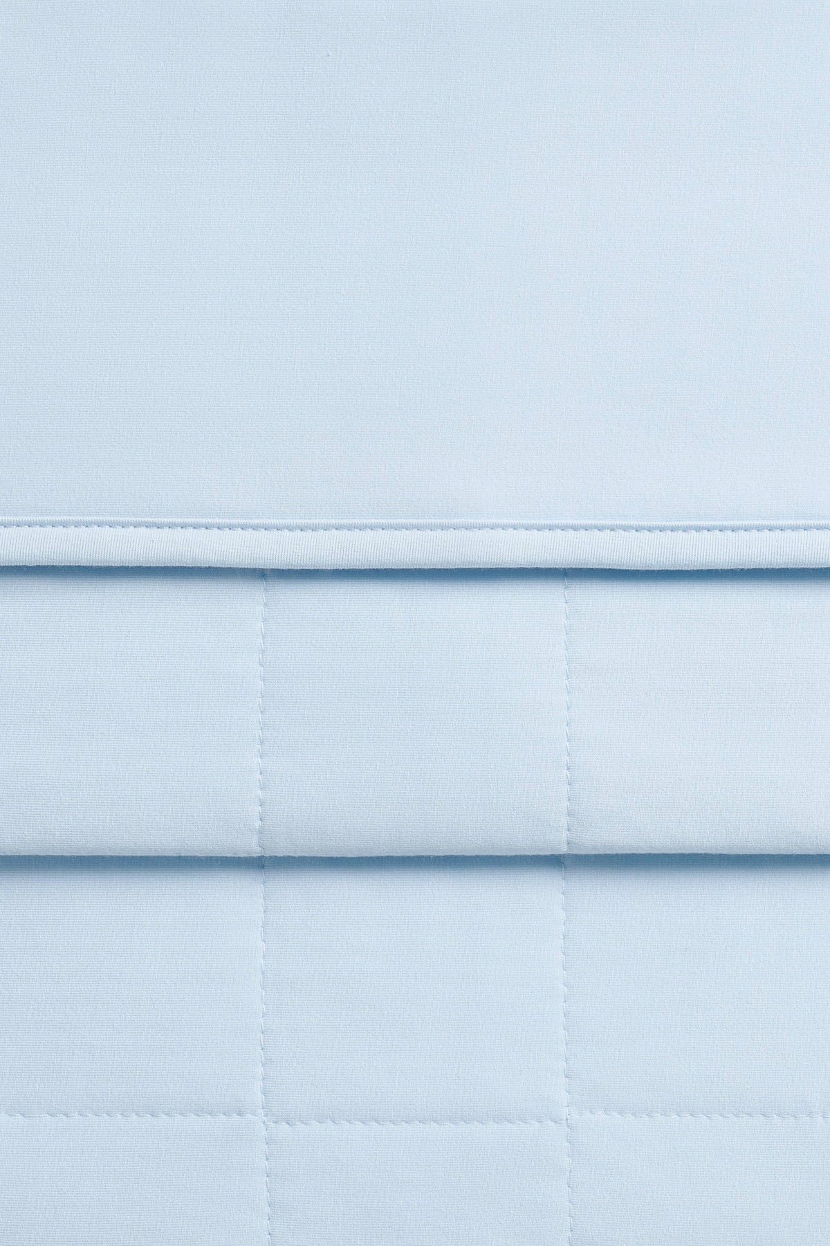 Close up of quilted backing and smooth top side of the Adult Quilted Blanket in Breeze 1.0