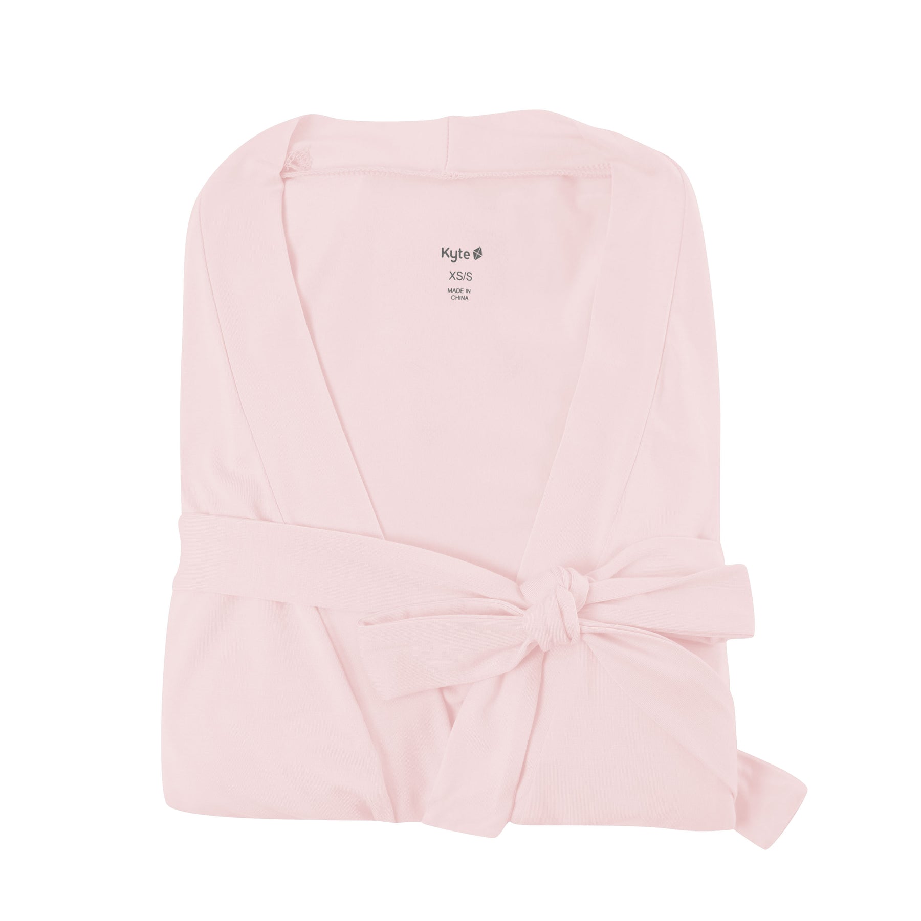 Folded blush pink robe on white backdrop