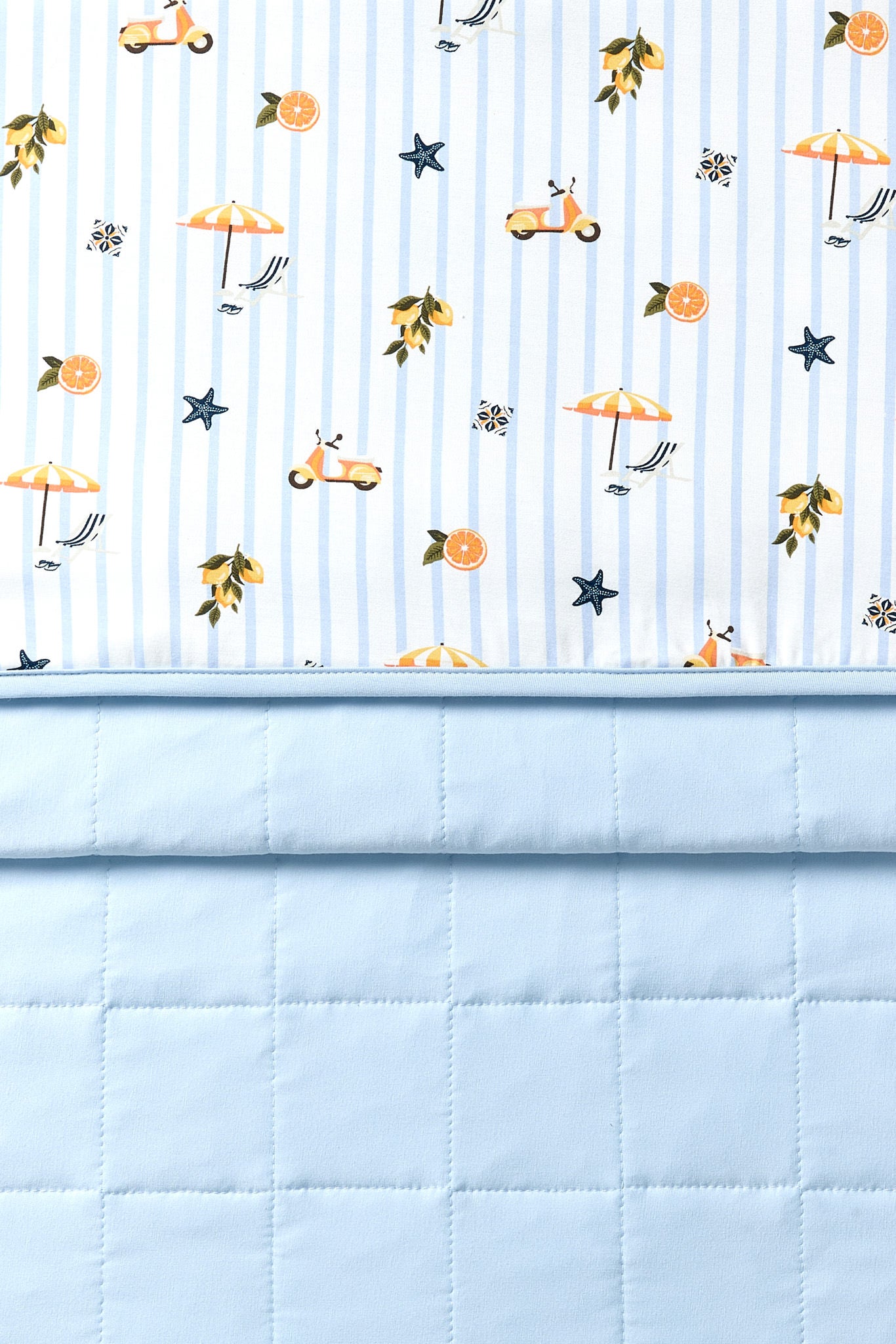 Close up of the Youth Blanket in Amalfi Coast 1.0 showing the quilted light blue backing and smooth printed top layer