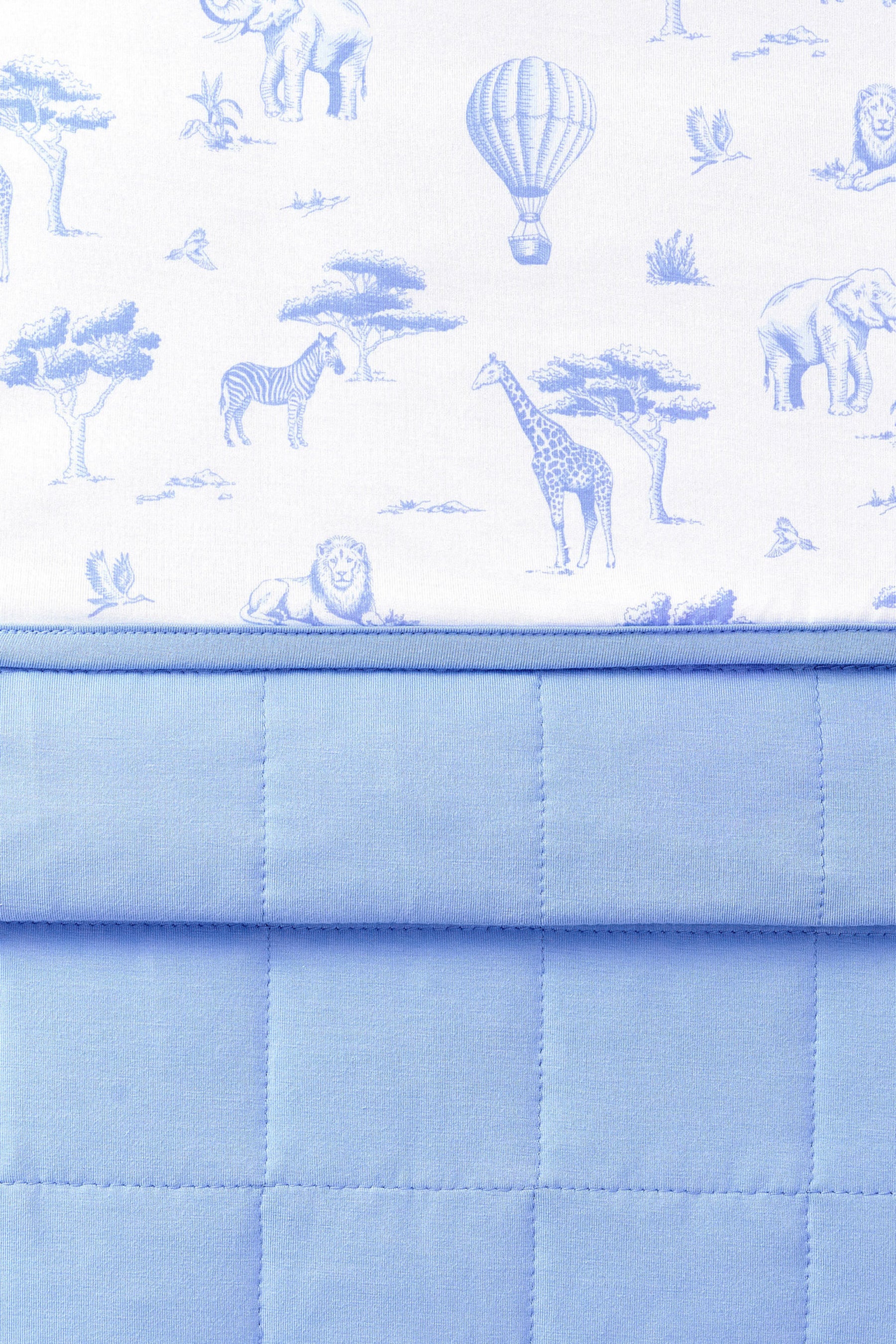 Close up of the Youth Blanket in Toile Safari 1.0 showing the quilted blue backing and smooth printed top layer