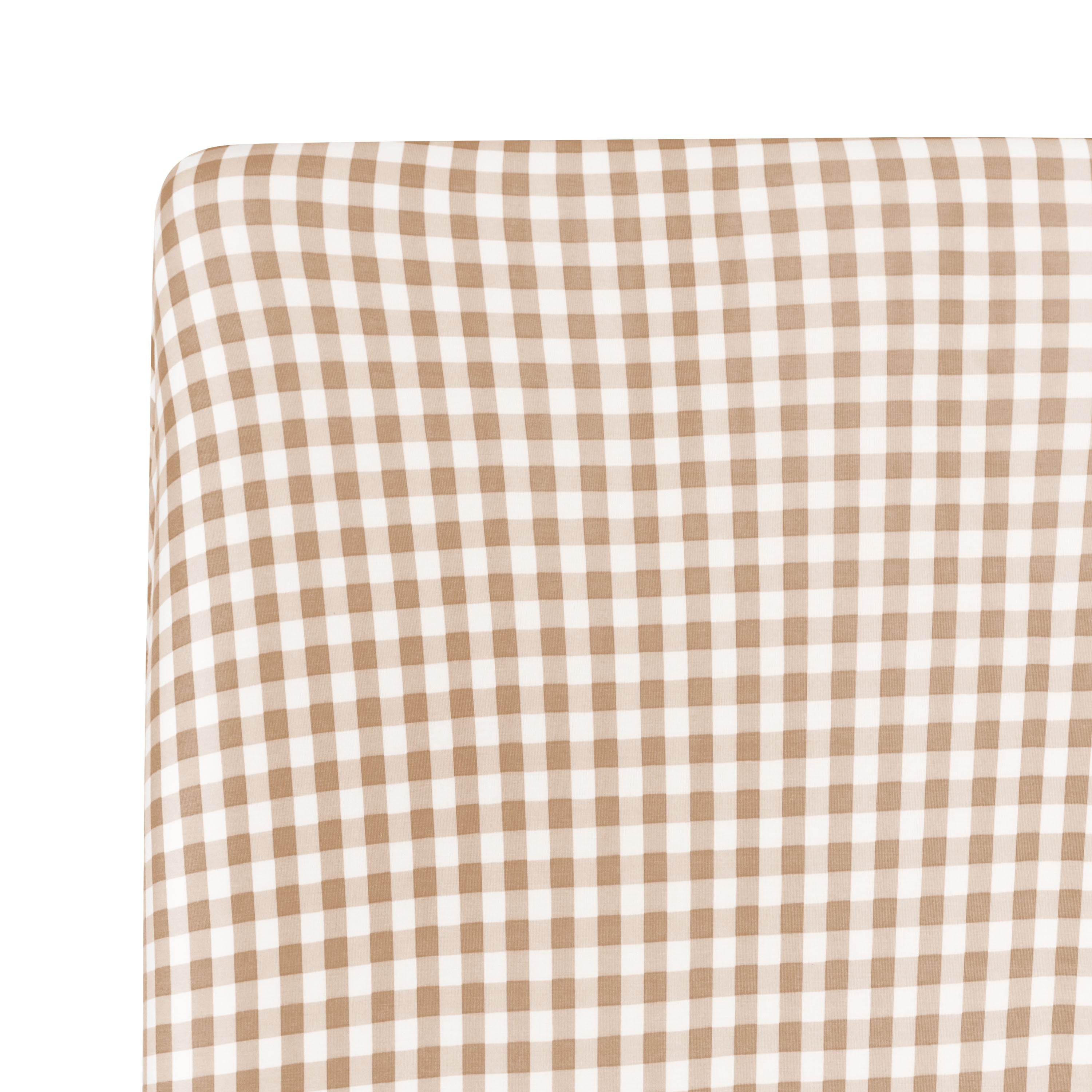 Close up of a corner of the Crib Sheet in Gingham Bisque shown on a crib mattress