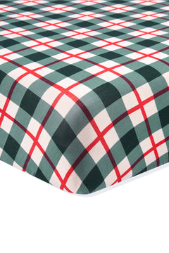 A close-up of a plaid fabric surface, likely a fitted sheet or blanket, featuring a green, white, and red tartan pattern on a white background.