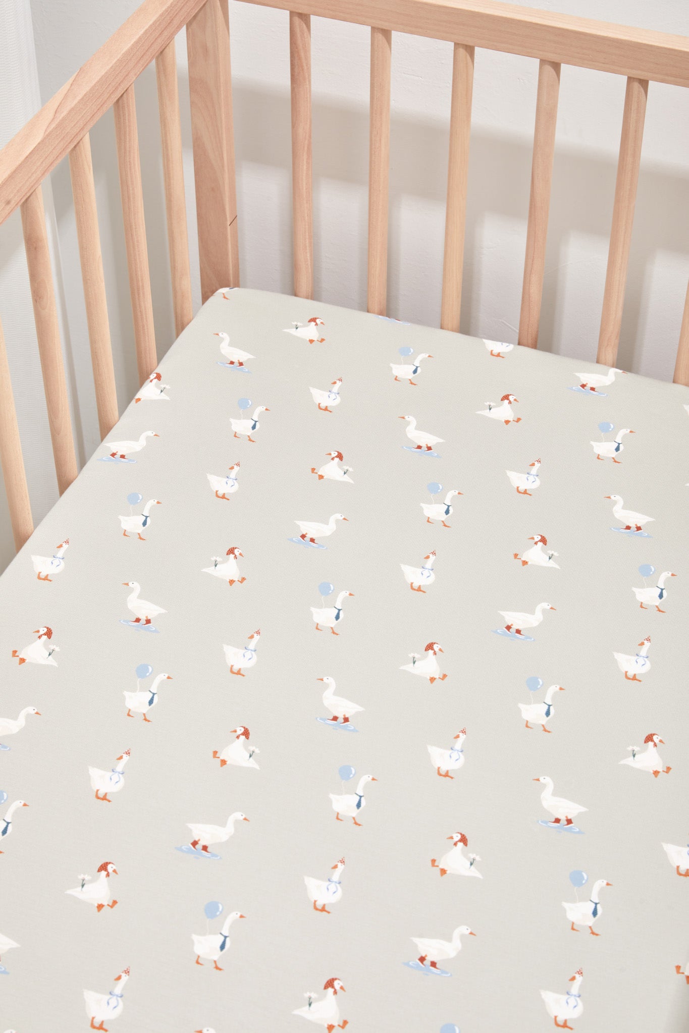 Crib Sheet placed in Oat Silly Goose print in a crib