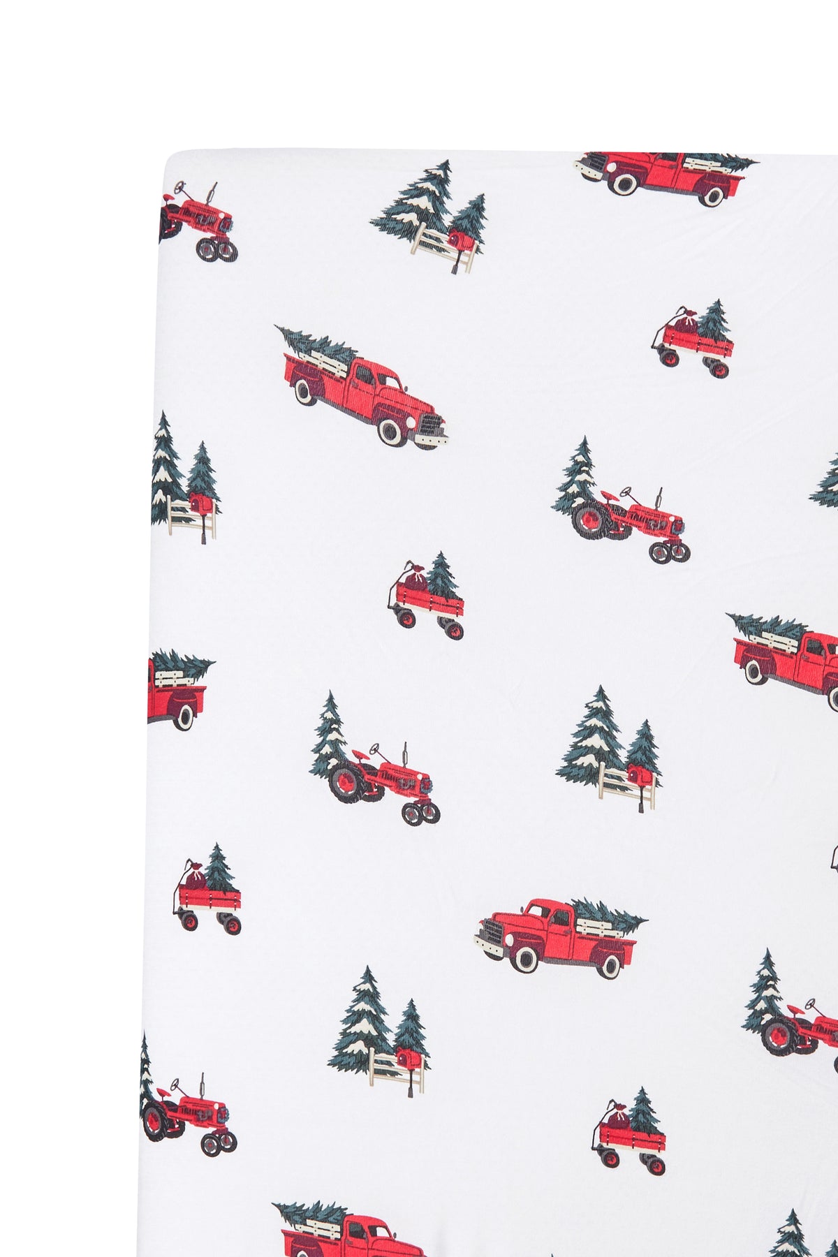 White fabric with a repeating pattern of red vintage pickup trucks carrying Christmas trees, alongside dark green pine trees and small wooden fence posts.