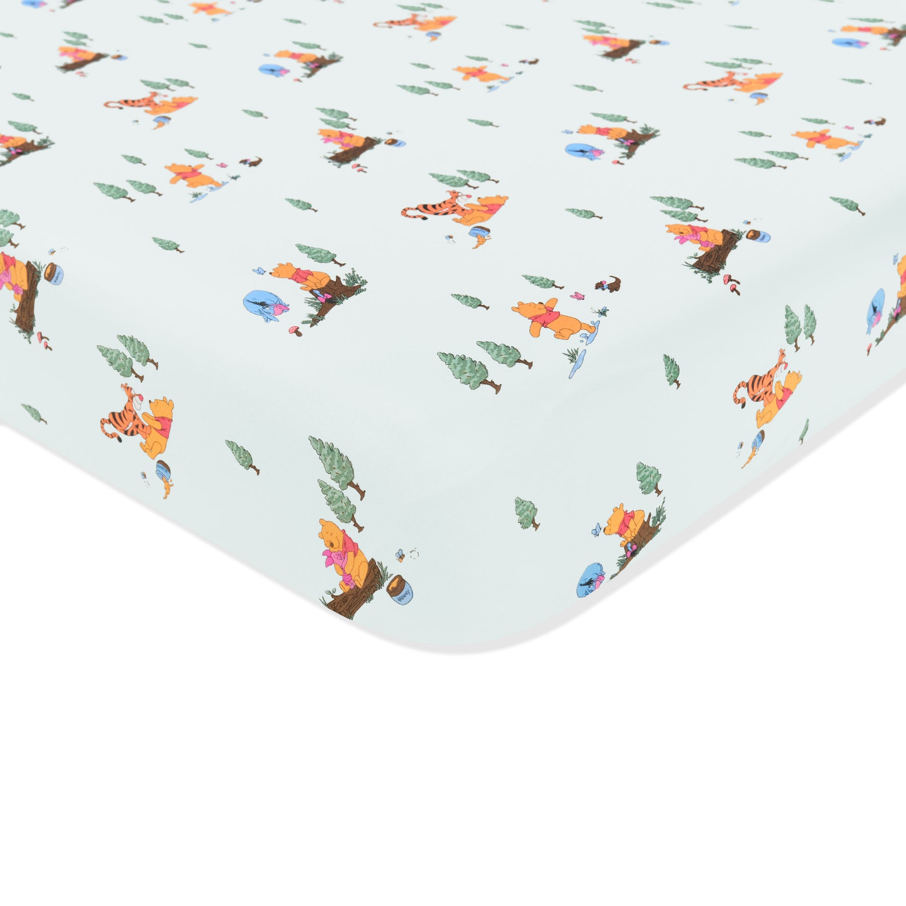 Corner of the Crib Sheet in Winnie the Pooh Hundred Acre Wood shown on a crib mattress