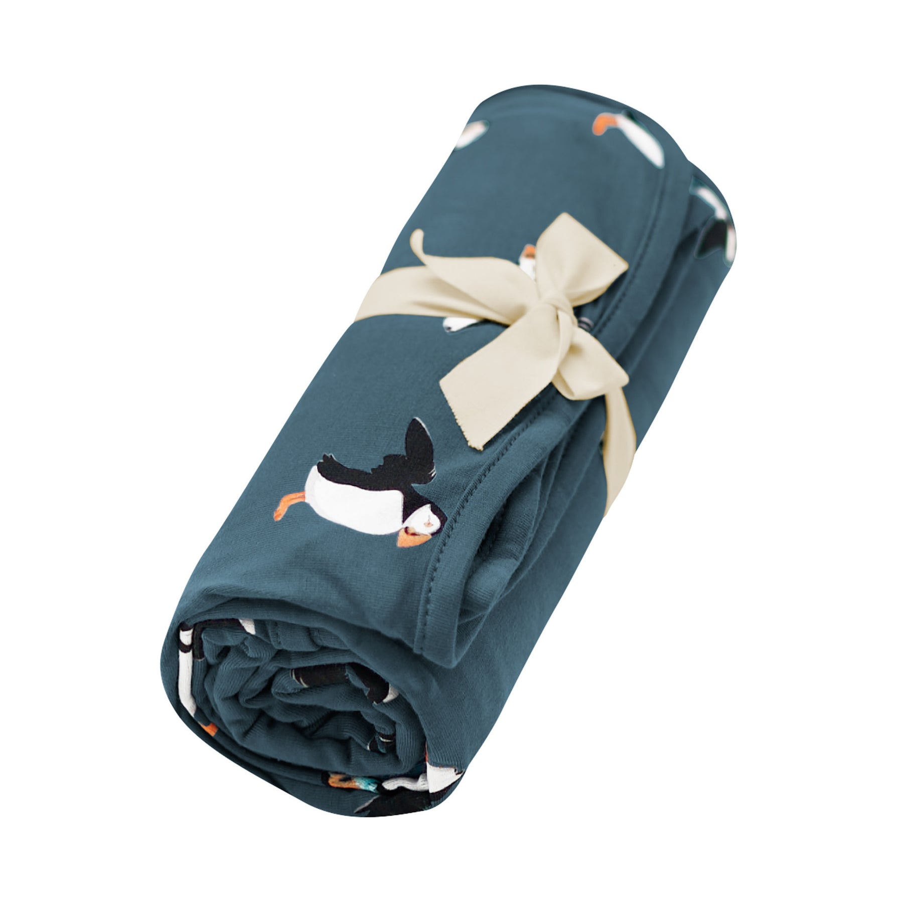 Swaddle Blanket in Puffin shown rolled in its packaging tied with a linen bow