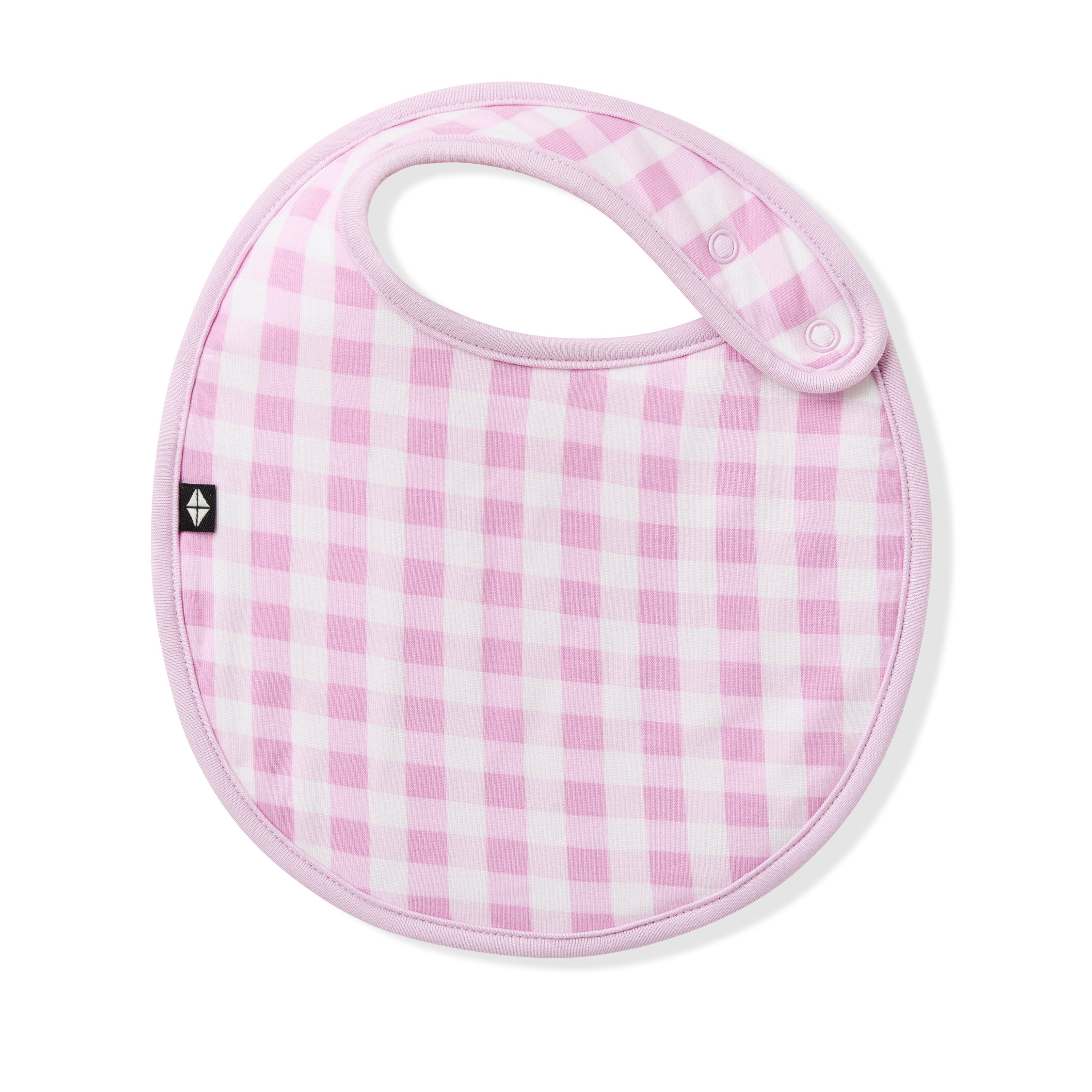The front of the Cushy Bib in Gingham Thistle showing the snap closures laid on a white surface