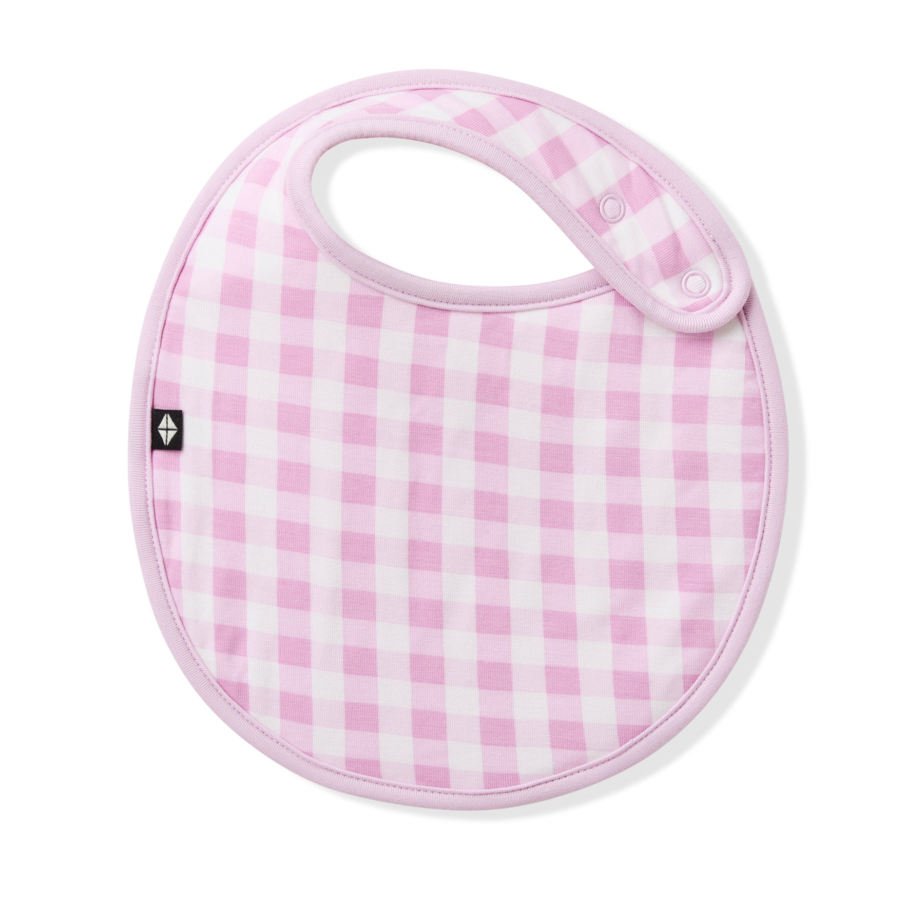 The front of the Cushy Bib in Gingham Thistle showing the snap closures laid on a white surface