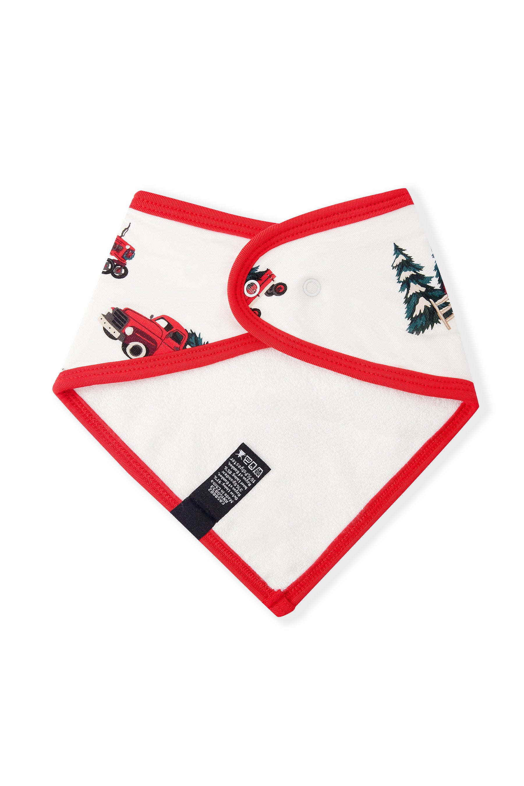 A white baby bib with red trim and a holiday print featuring red trucks carrying Christmas trees and a green pine tree, shown on a plain white background.