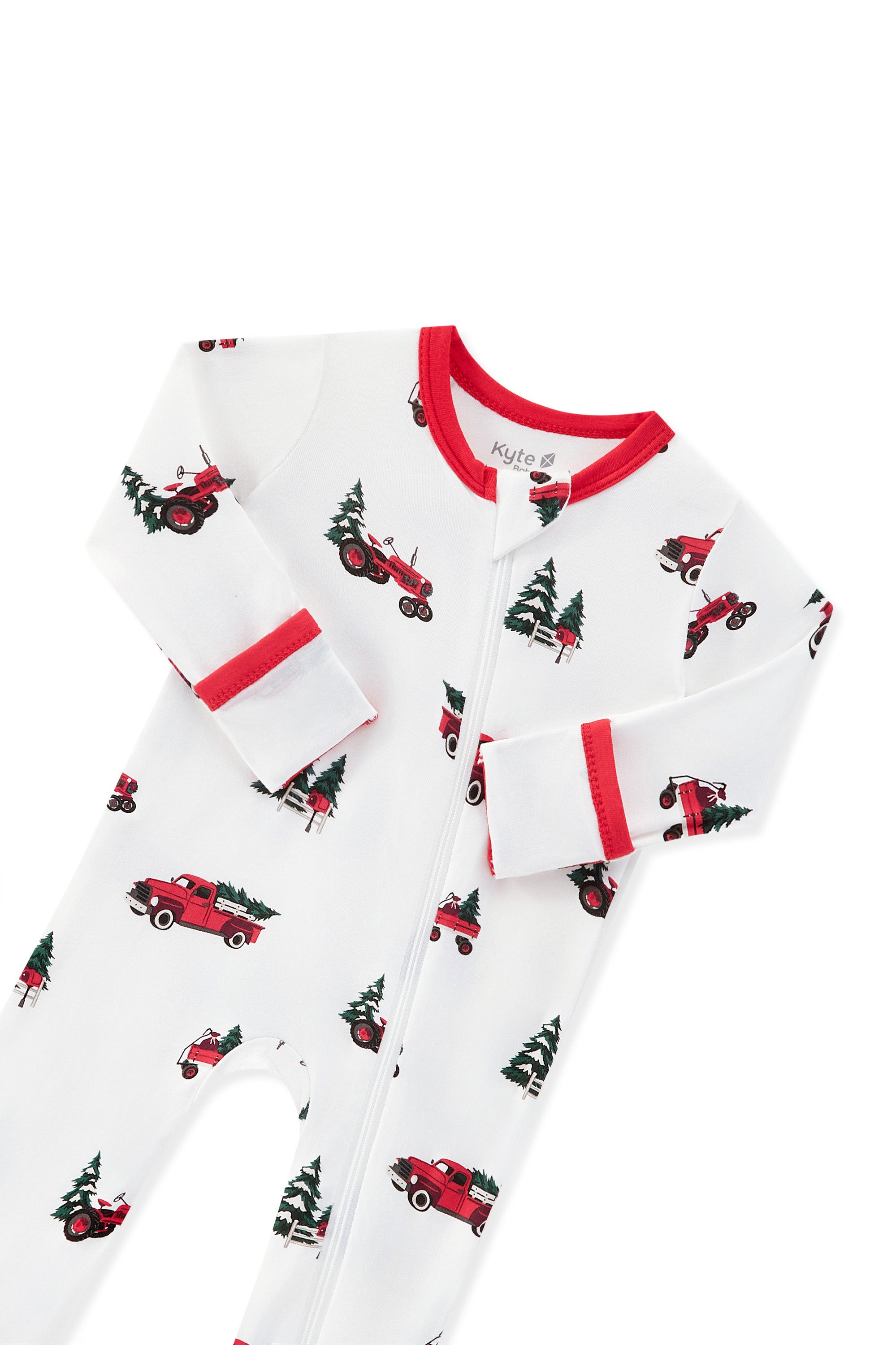 A white long-sleeve zippered footie with a red collar and cuffs, featuring an all-over print of red pickup trucks carrying Christmas trees displayed on a white background