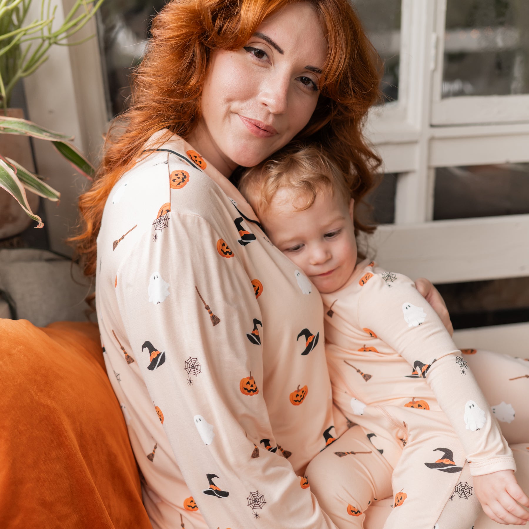 Close up of mother wearing the Zippered Romper in Bewitched matching her son who is on her lap wearing the Zippered romper in Bewitched