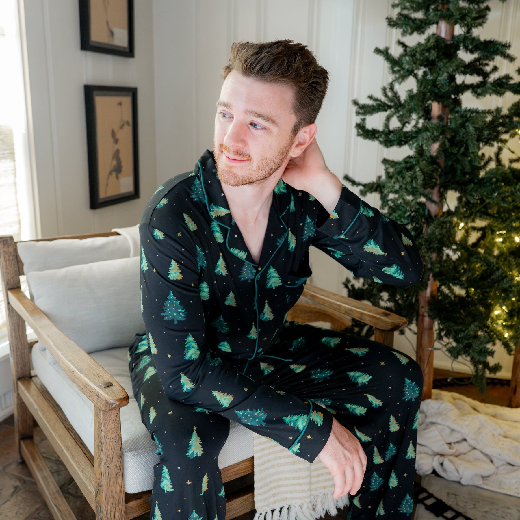 Male model sitting on a chair wearing the Men's Long Sleeve Pajama Set in Twinkle Tree