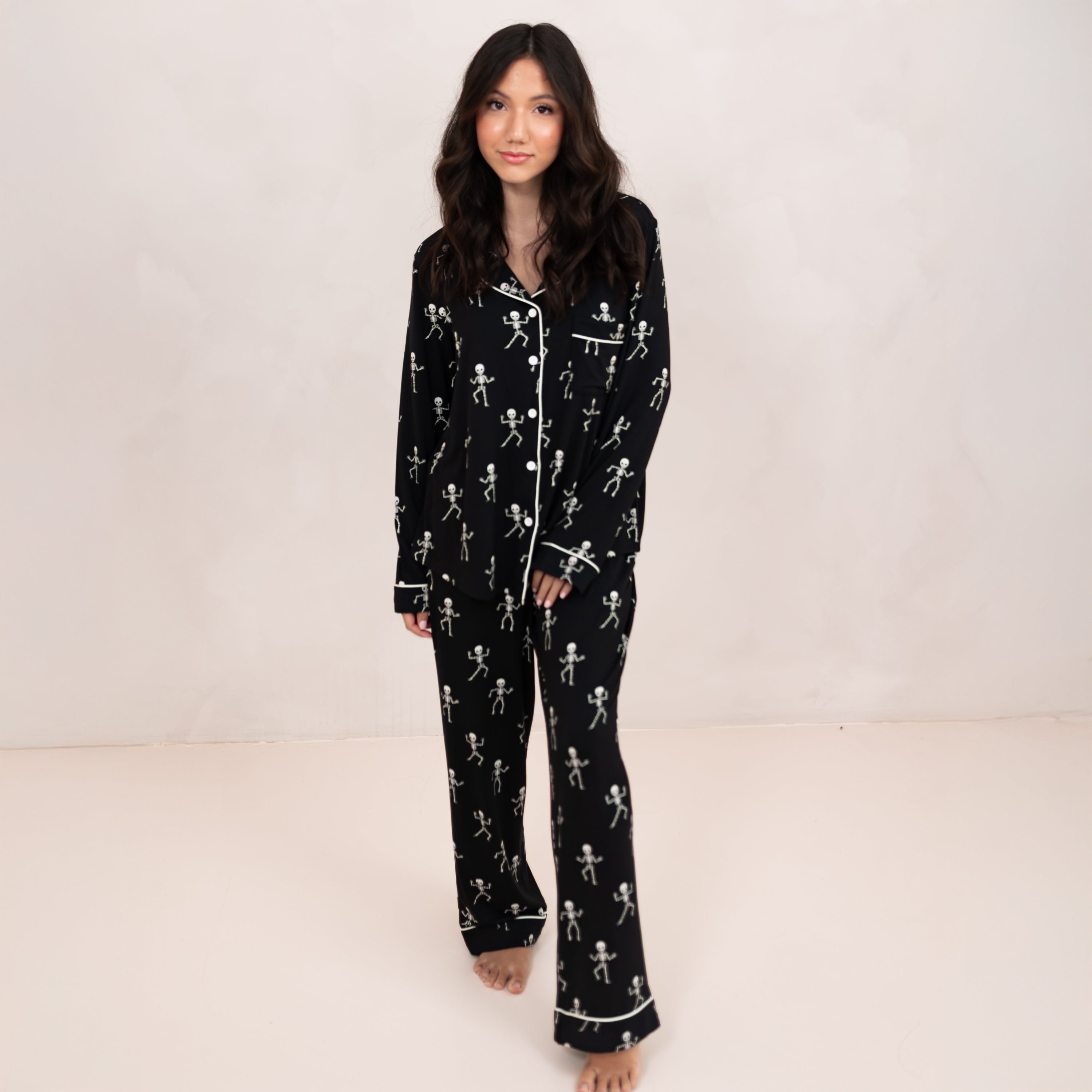 Female model walking wearing the Long-Sleeved Women's Pajama Set in Skeleton in front of a light beige backdrop