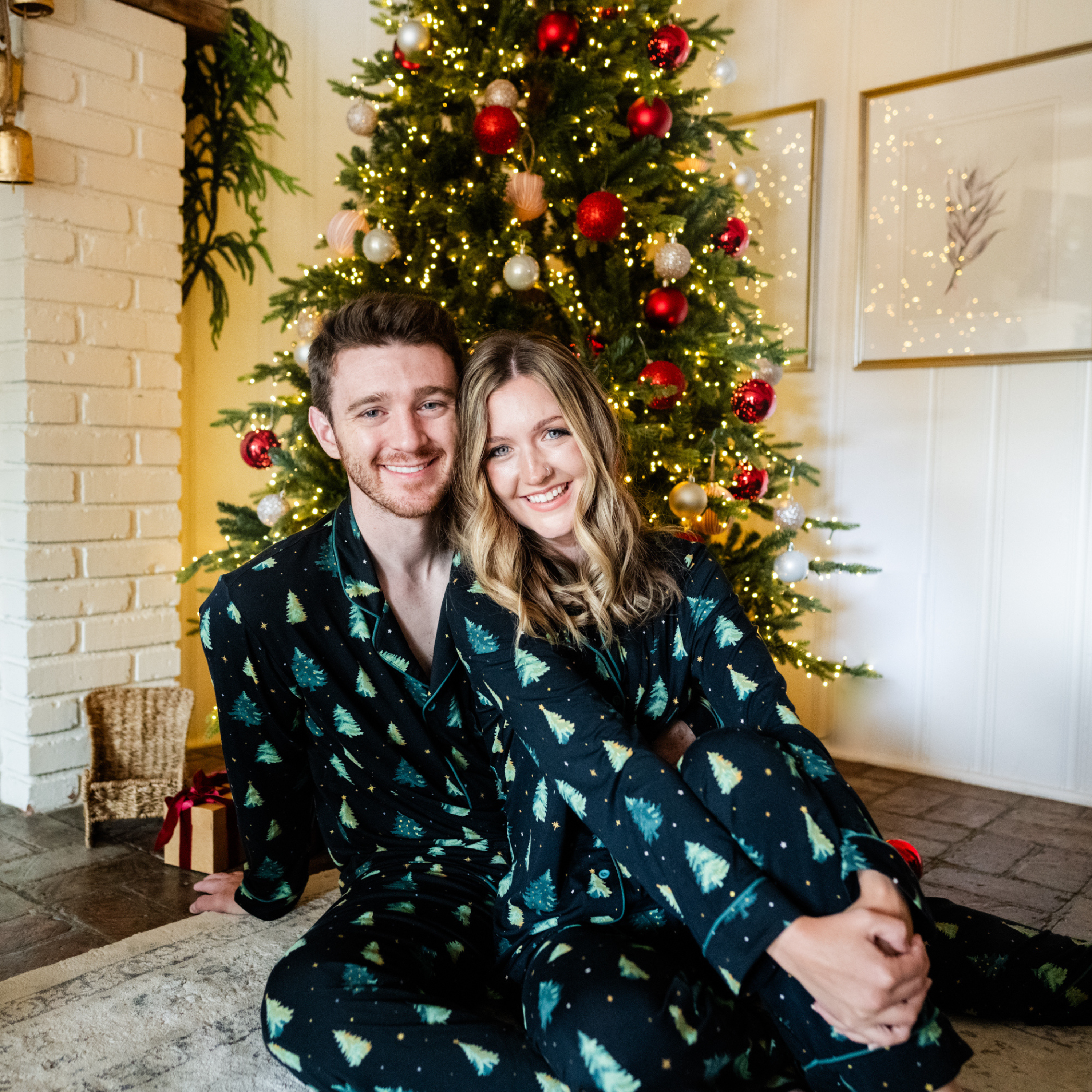 Wife sitting on husbands lap on the floor both matching in the Men's and Women's Long Sleeve Pajama Set in Twinkle Tree
