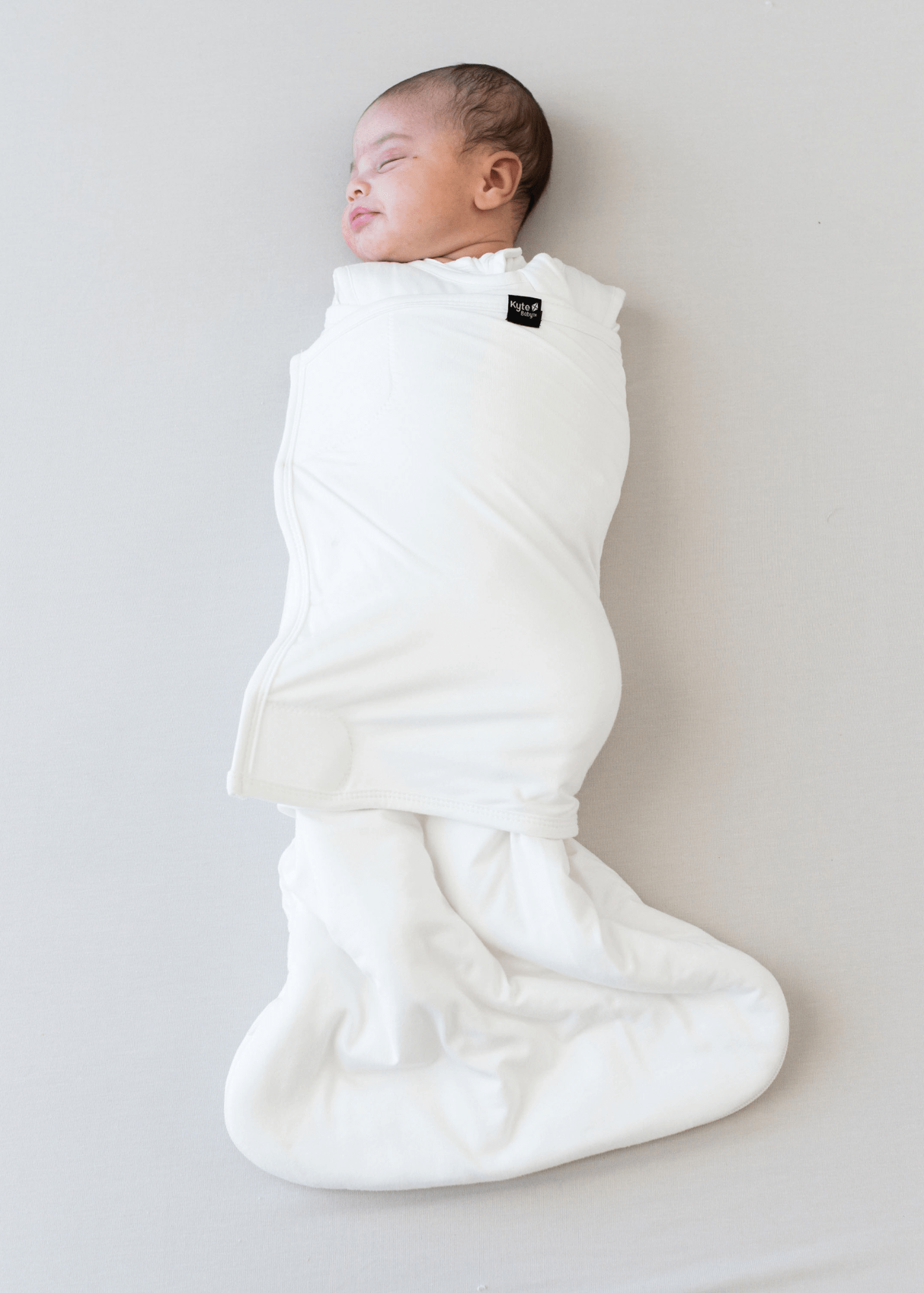 Baby sleeping wearing kyte baby sleep bag swaddler in cloud