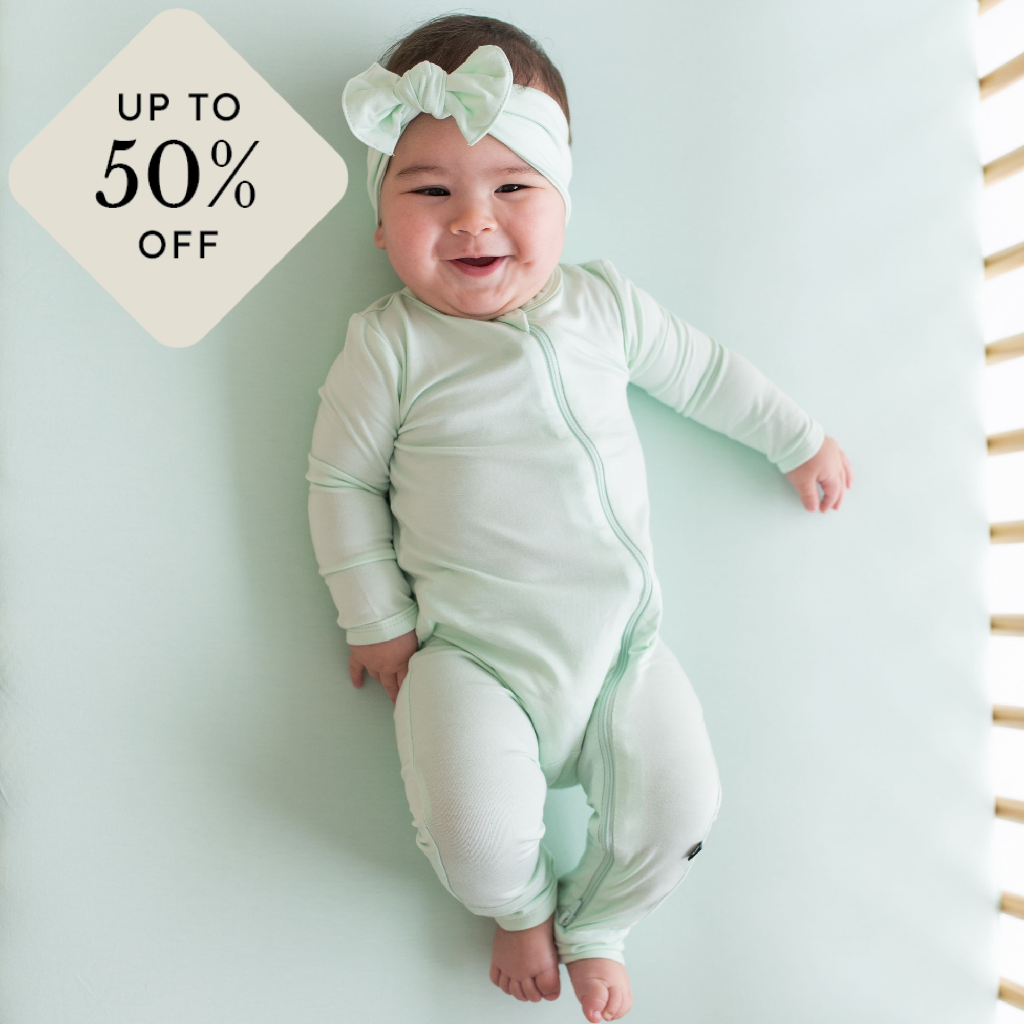 baby in mint zippered romper with up to 50% off icon