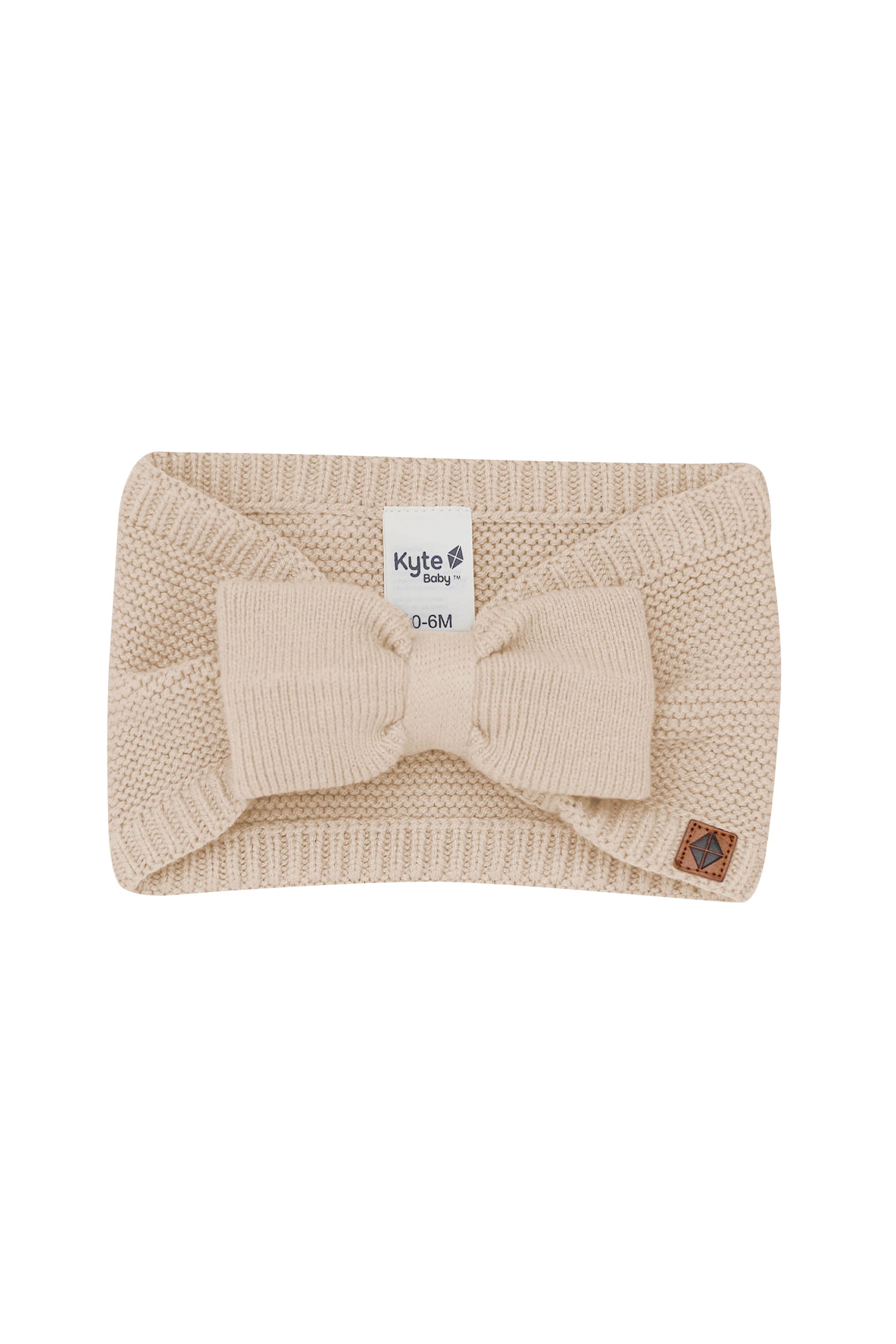 Product photo of the Chunky Knit Bow Headband in Almond with the Kyte Baby vegan leather tag visible