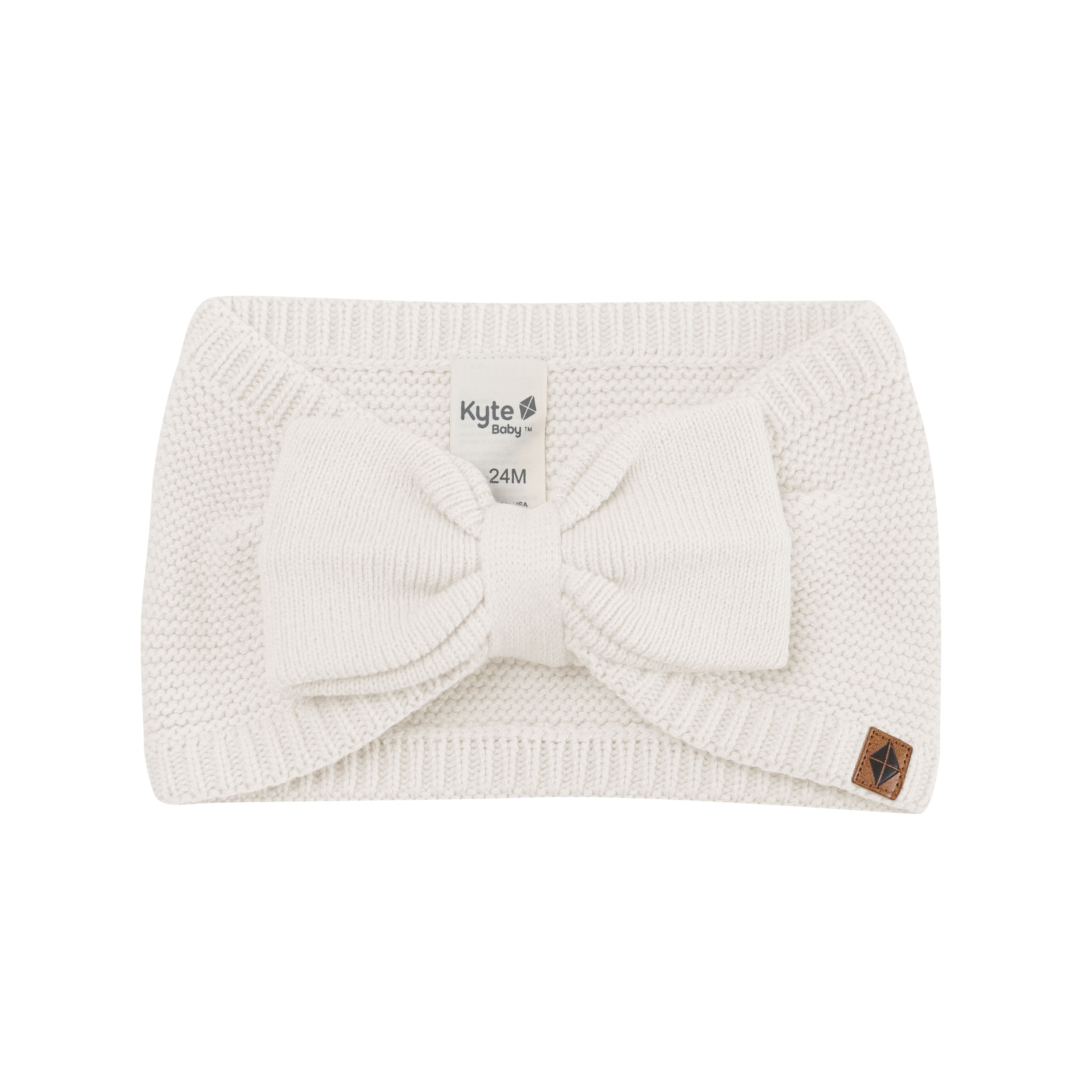 Product photo of the Chunky Knit Bow Headband in Oat with the Kyte Baby vegan leather tag visible