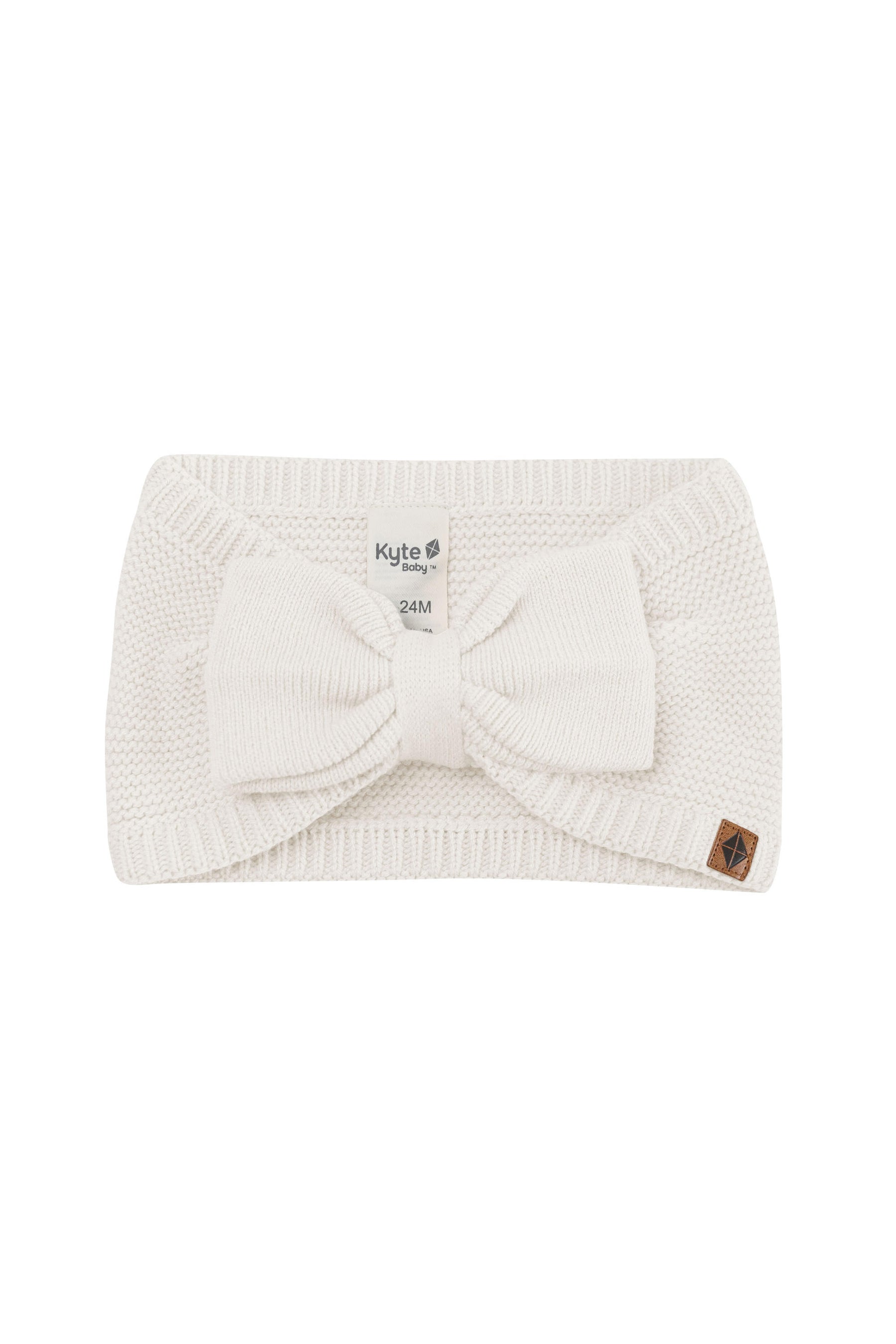 Product photo of the Chunky Knit Bow Headband in Oat with the Kyte Baby vegan leather tag visible
