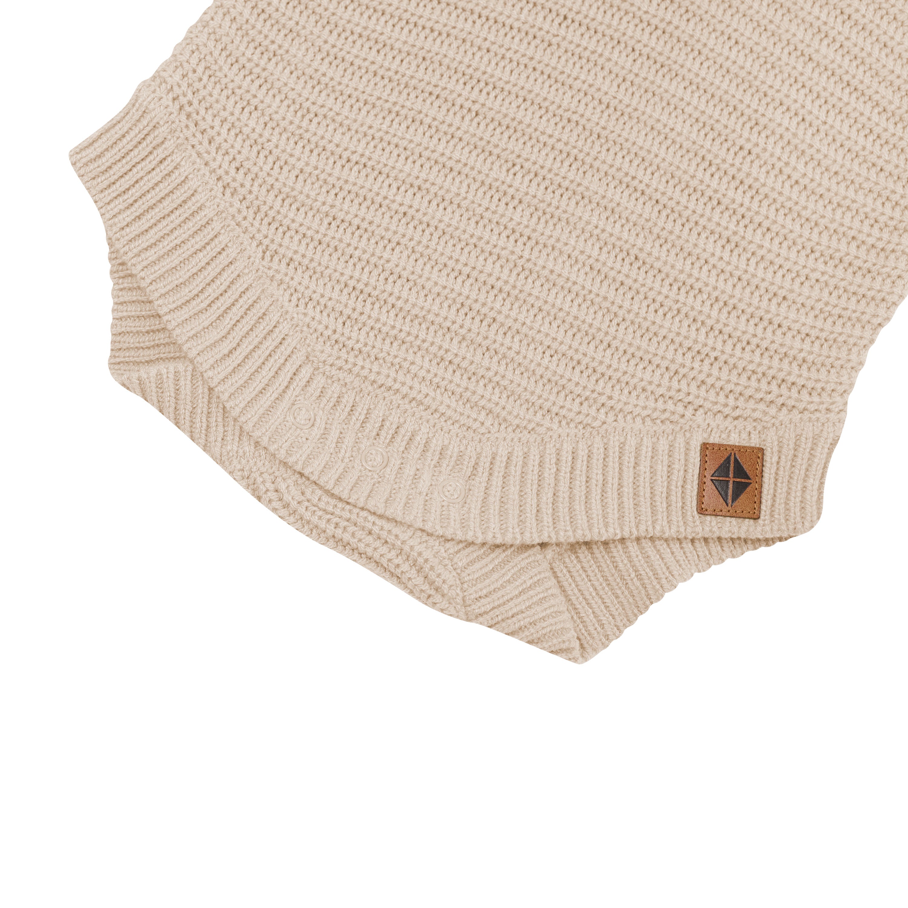 Close up of the snap closure on the Chunky Knit Romper in Almond with the Kyte Baby Vegan leather tag visible