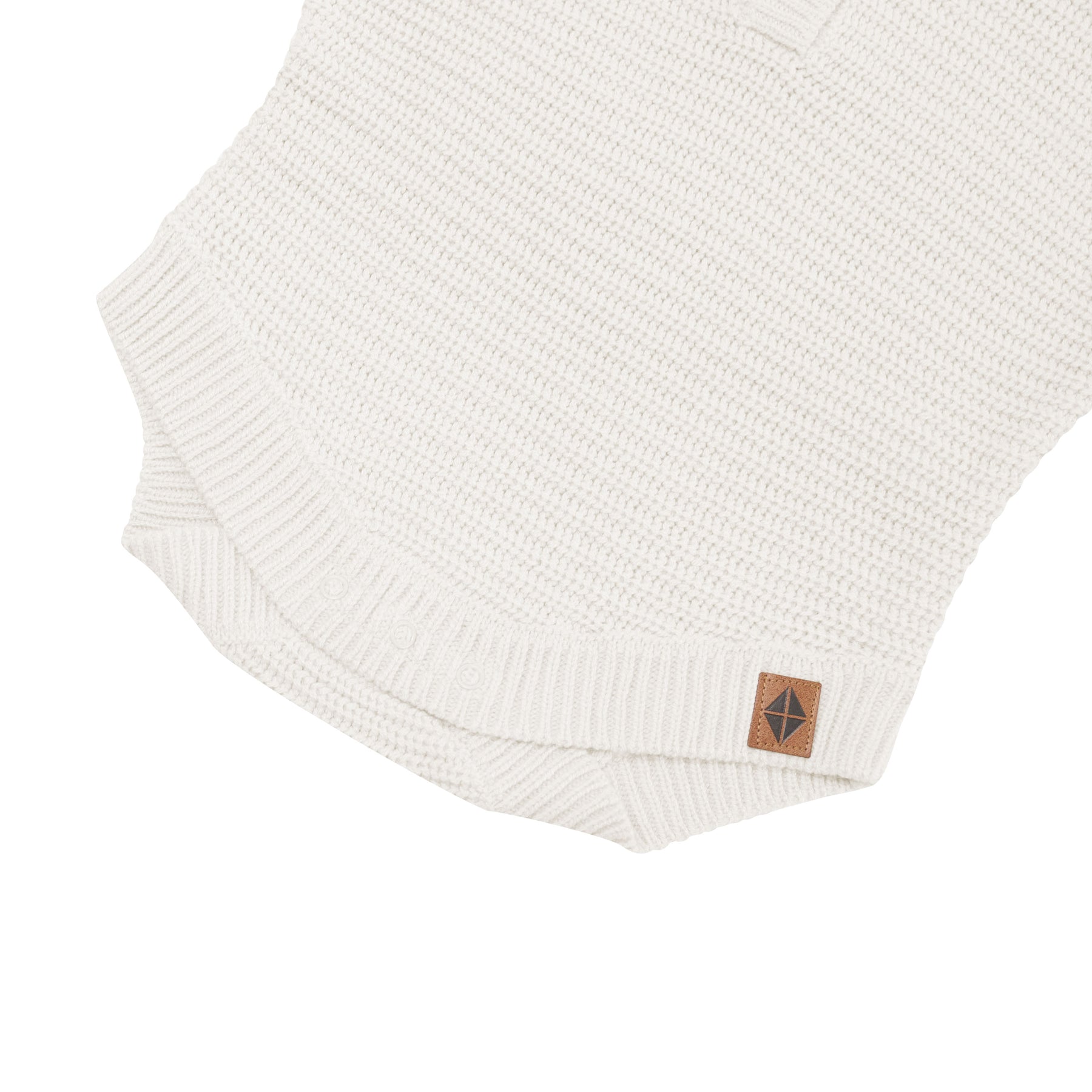 Snap closure shown on the Chunky Knit Romper in Oat with the Kyte Baby vegan leather tag visible