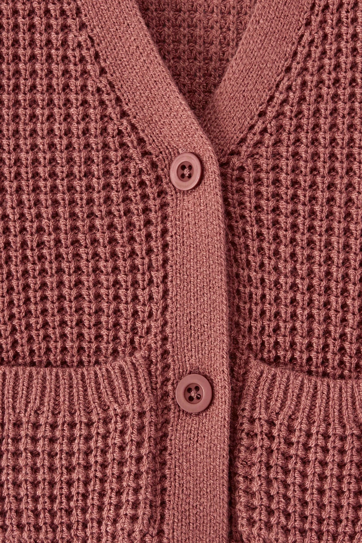 Close-up of a textured knit cardigan in ember color, featuring a waffle-weave pattern, ribbed trim, and two white buttons.