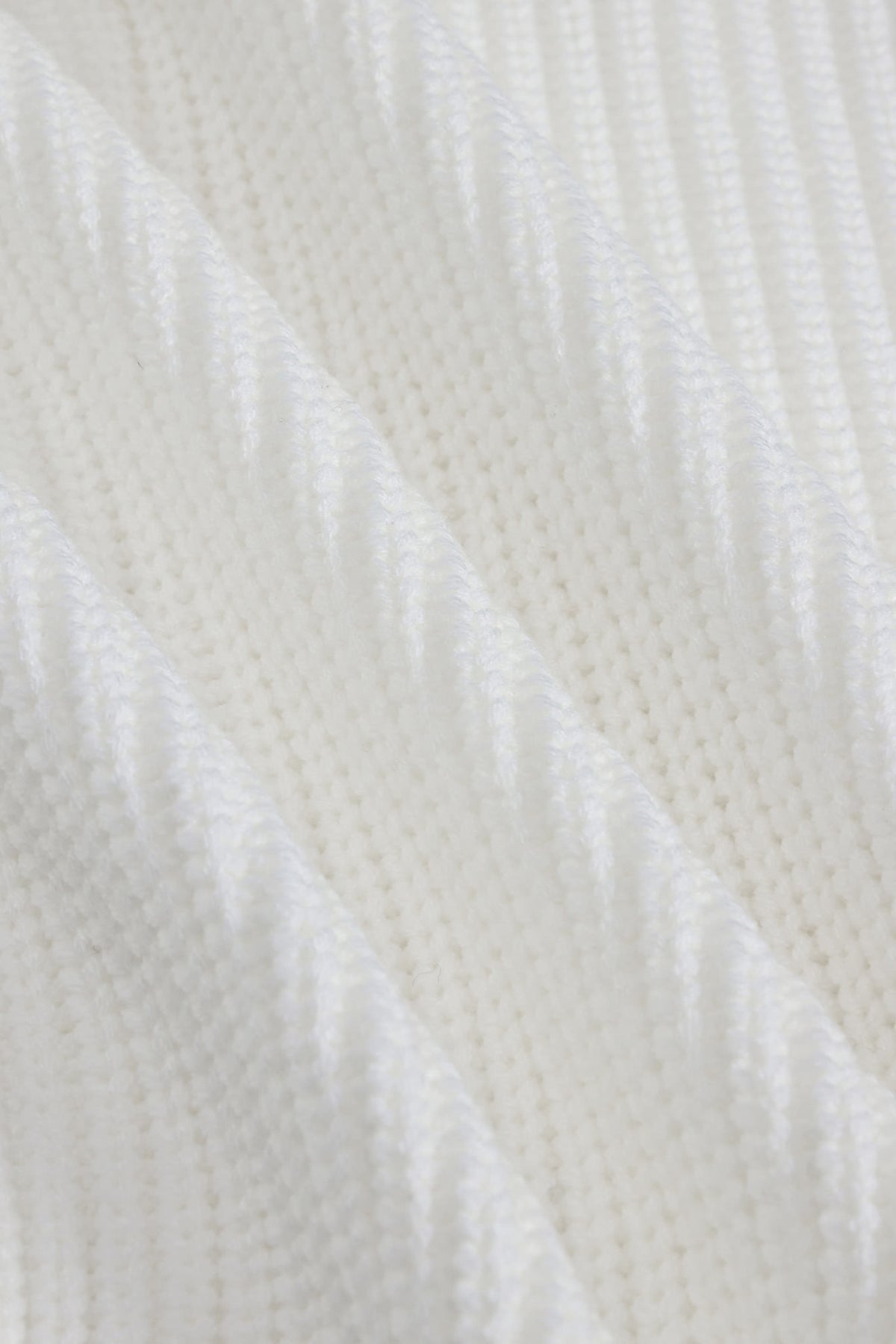 A close-up of a white textured knit fabric with a subtle diagonal ribbed pattern.