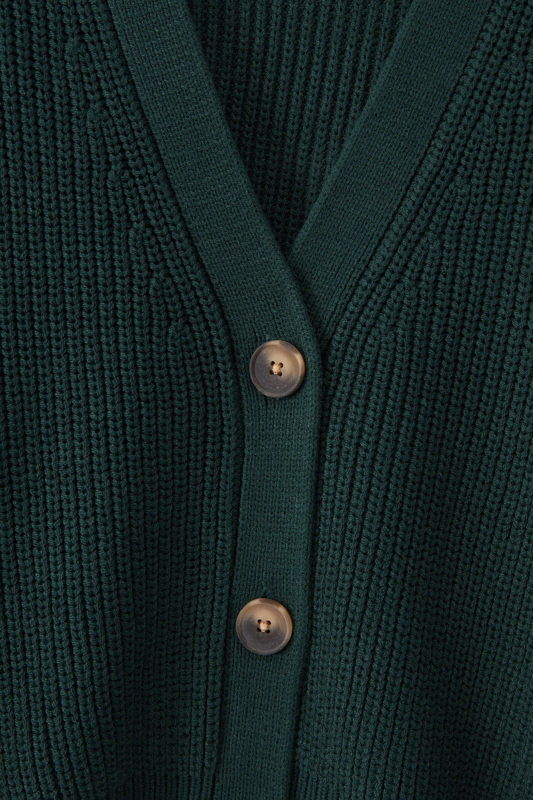 Close-up of a dark green ribbed knit cardigan with a V-neck and two metallic buttons.