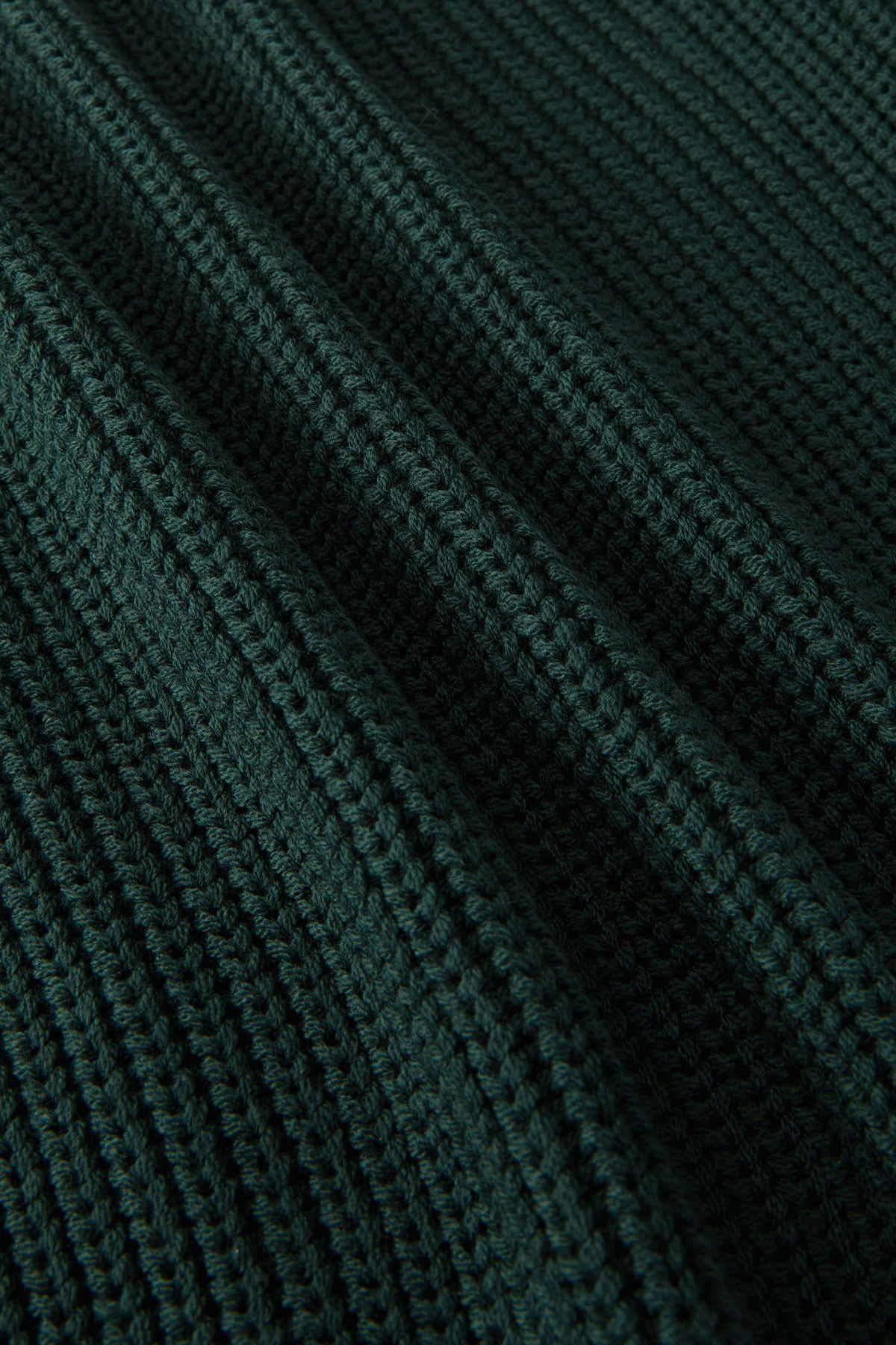 Close-up of a dark forest green ribbed knit fabric texture with a fine waffle pattern.