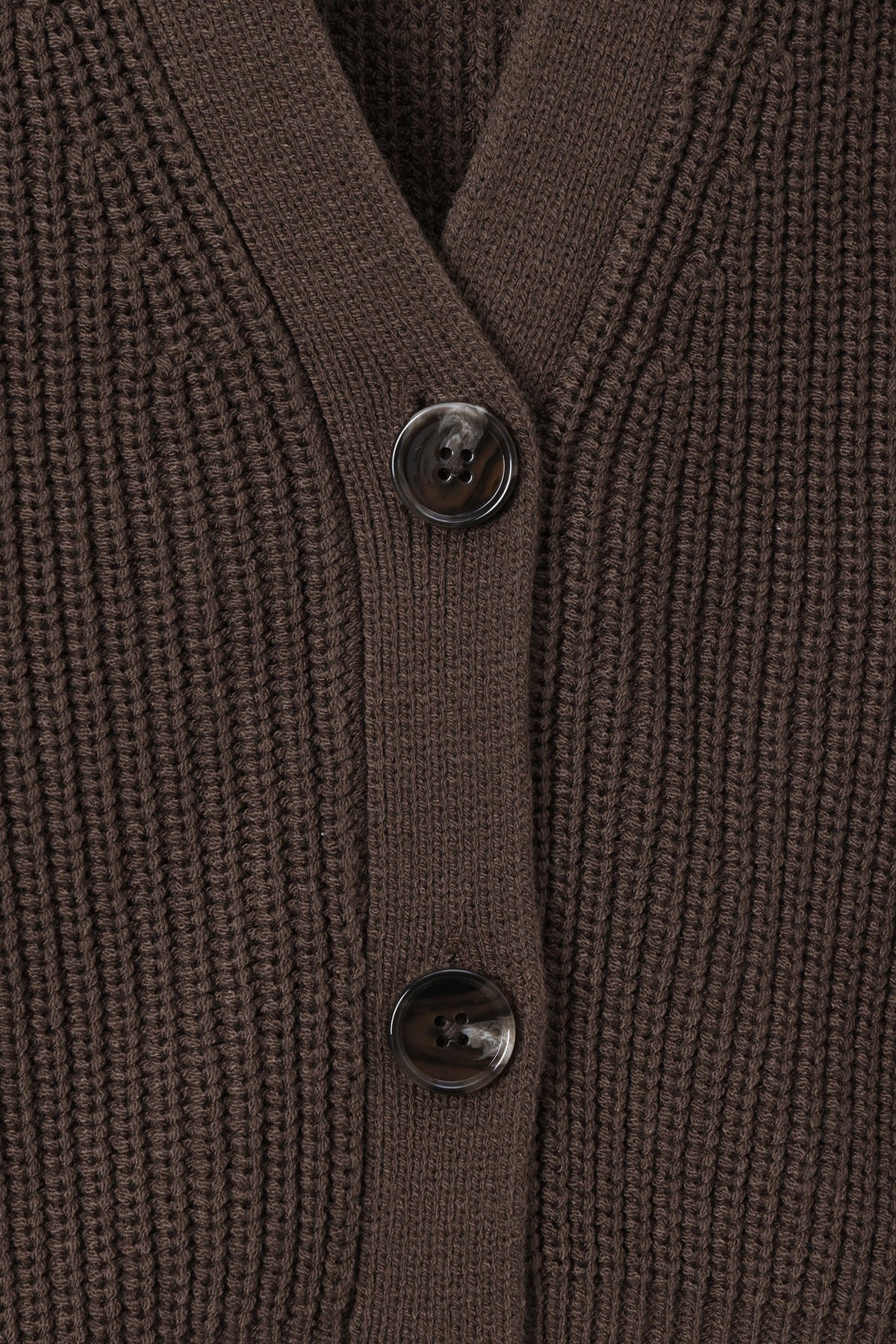Close-up of a ribbed knit cardigan in dark brown with two dark buttons on a matching brown background.