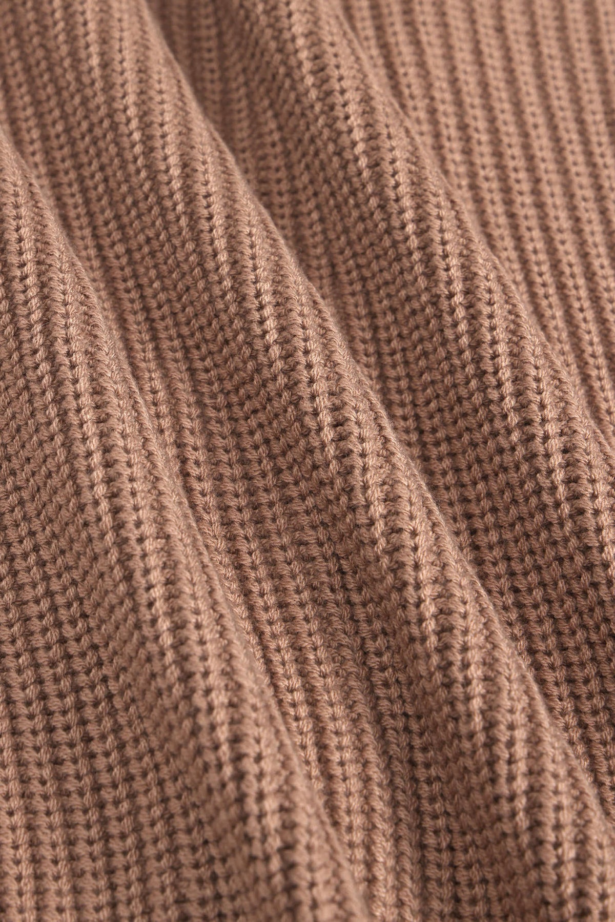 Close-up of a ribbed knit fabric in a warm taupe-brown color, showing the detailed texture and folds of the material.