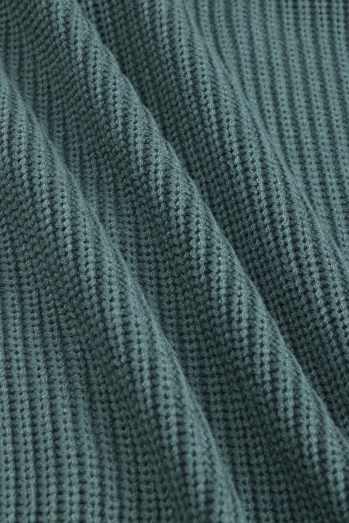 Close-up of a ribbed knit fabric in a muted blue-green color, showing the detailed texture and folds.