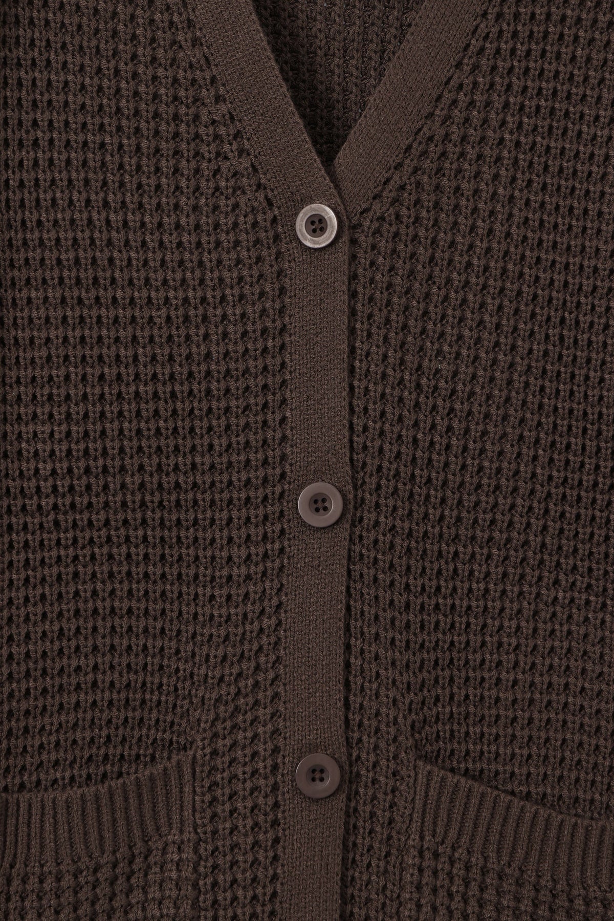 Close-up of a dark brown waffle-knit cardigan sweater showing the buttoned front and ribbed collar, cuffs, and hem.
