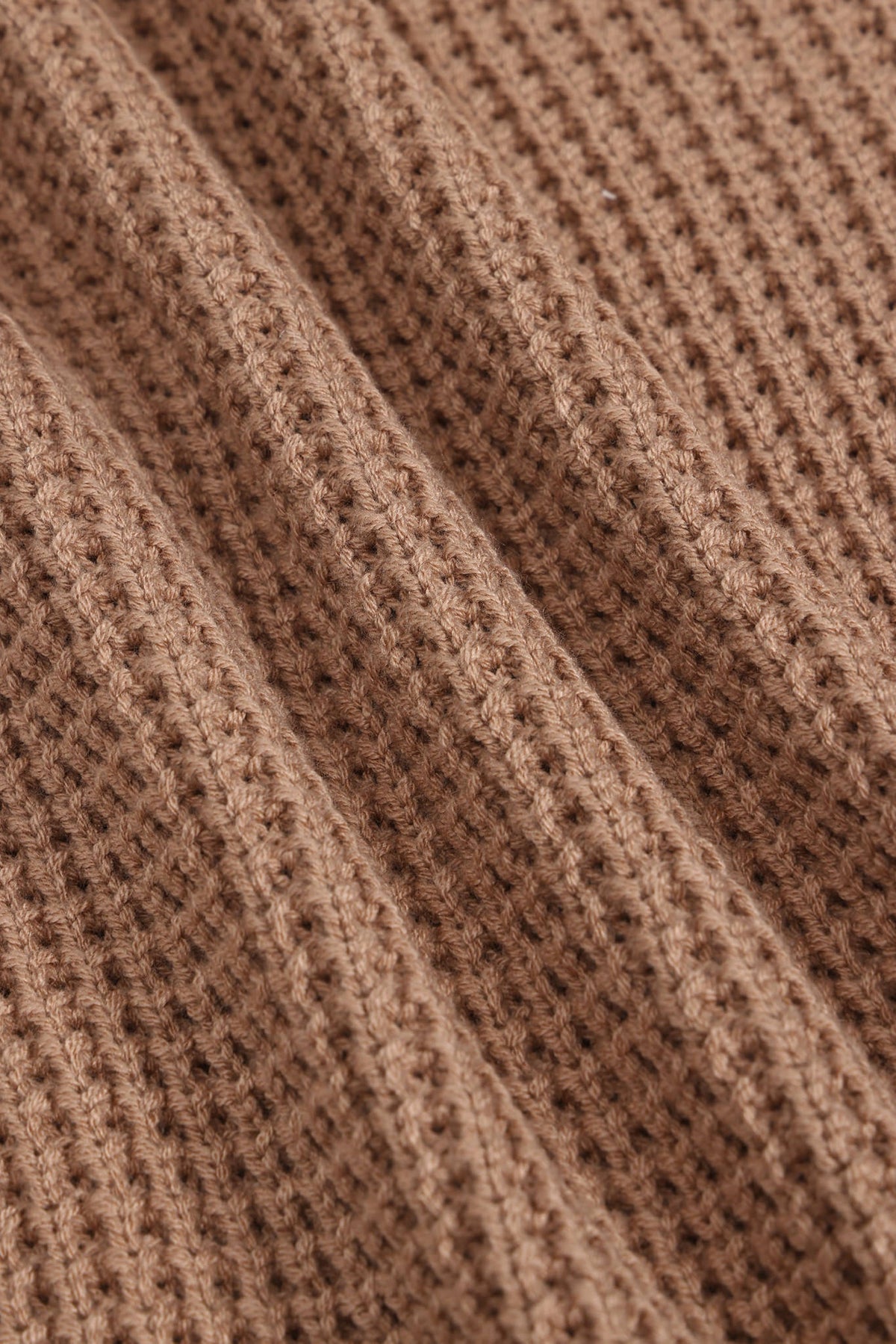 Close-up of a brown ribbed knit fabric texture with a waffle-like pattern.