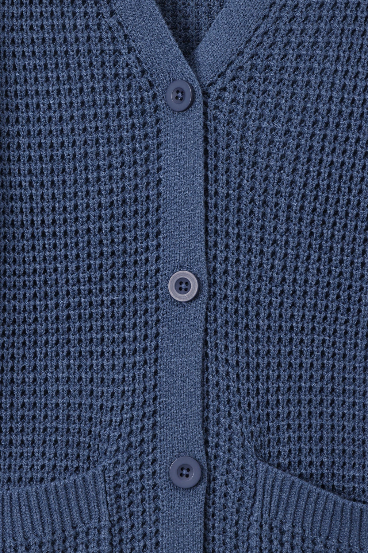 Close-up of a textured knit cardigan in a muted slate blue color, featuring a buttoned front closure and ribbed trim.