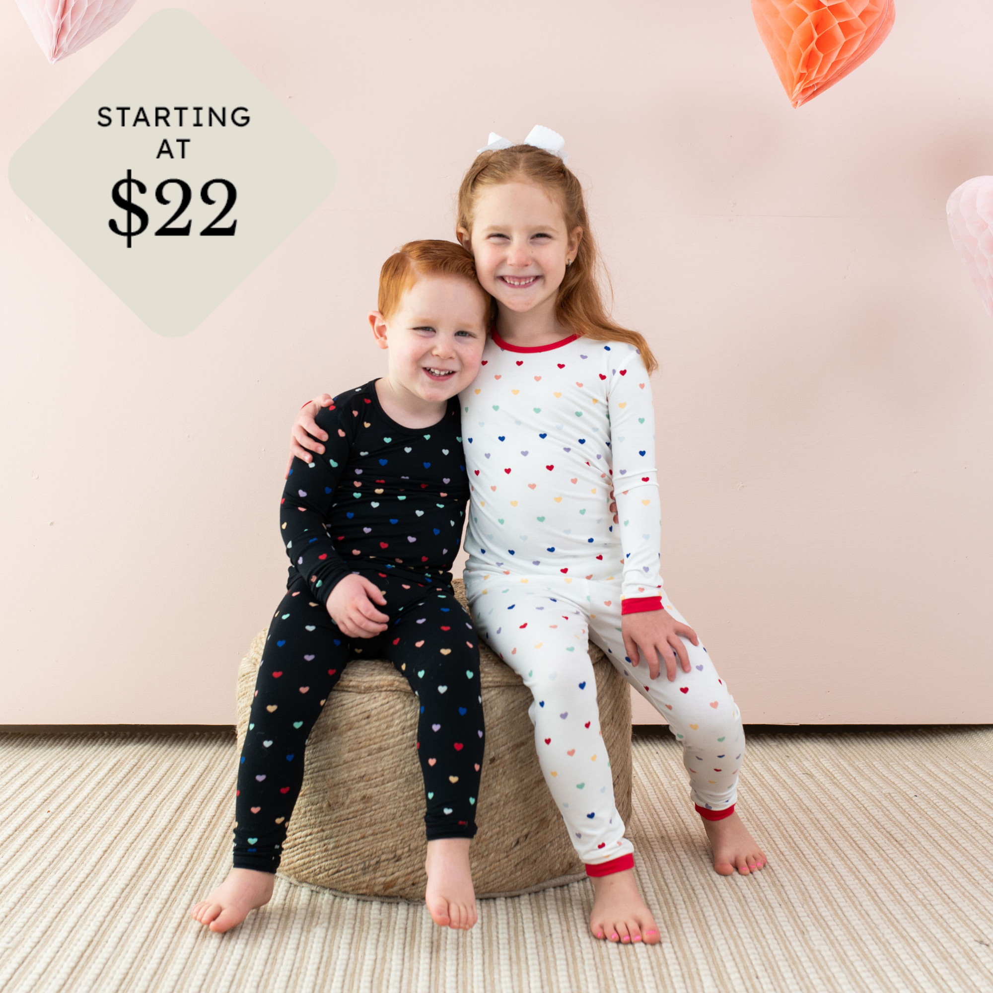 two toddlers in midnight rainbow heart and cloud rainbow heart long sleeve pajamas with starting at $22 icon