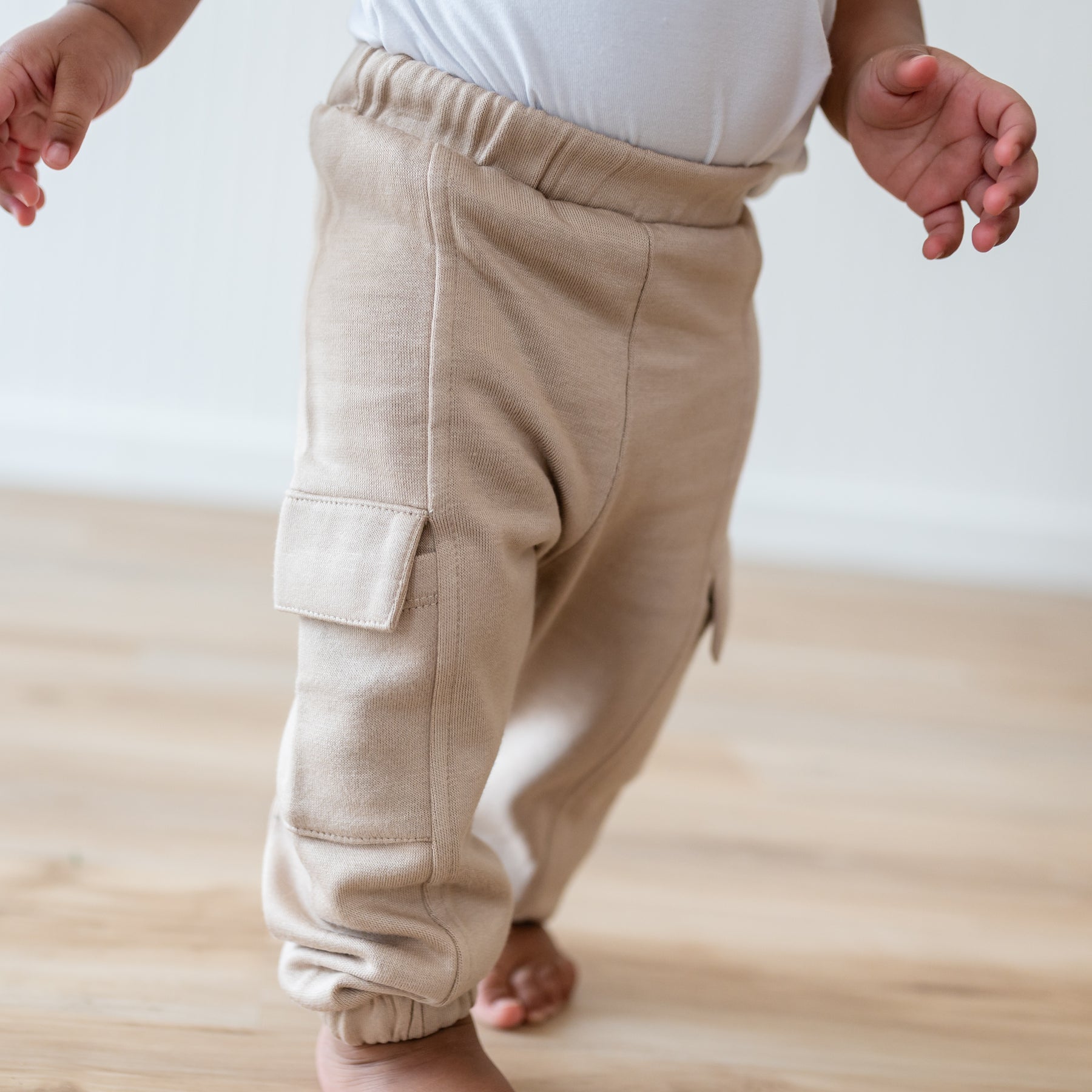 Close up of the Fleece Cargo Pants in Almond shown on a walking toddler