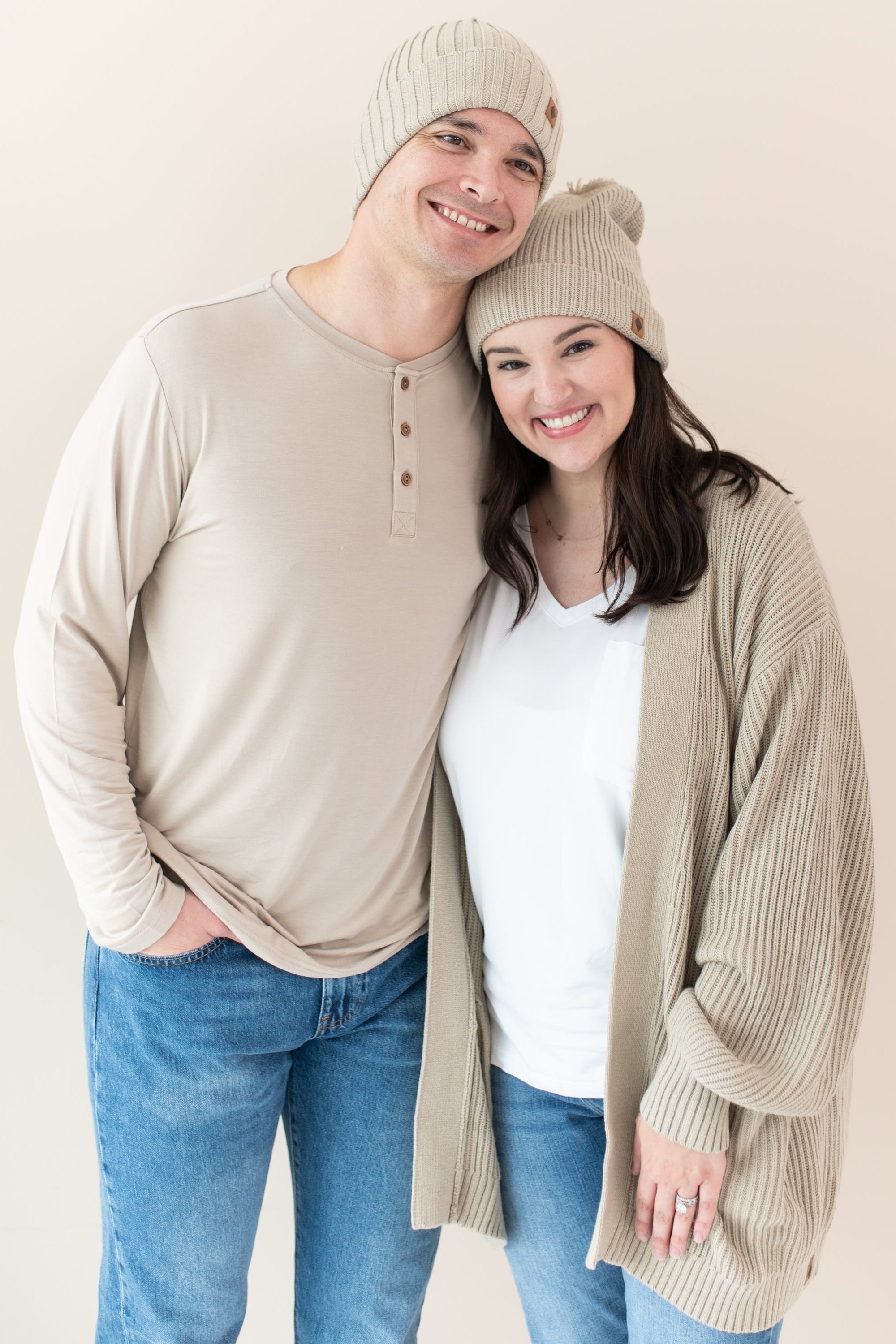 Couple modeling almond kyte pieces including men's henley tee, chunky knit cardigan and beanies
