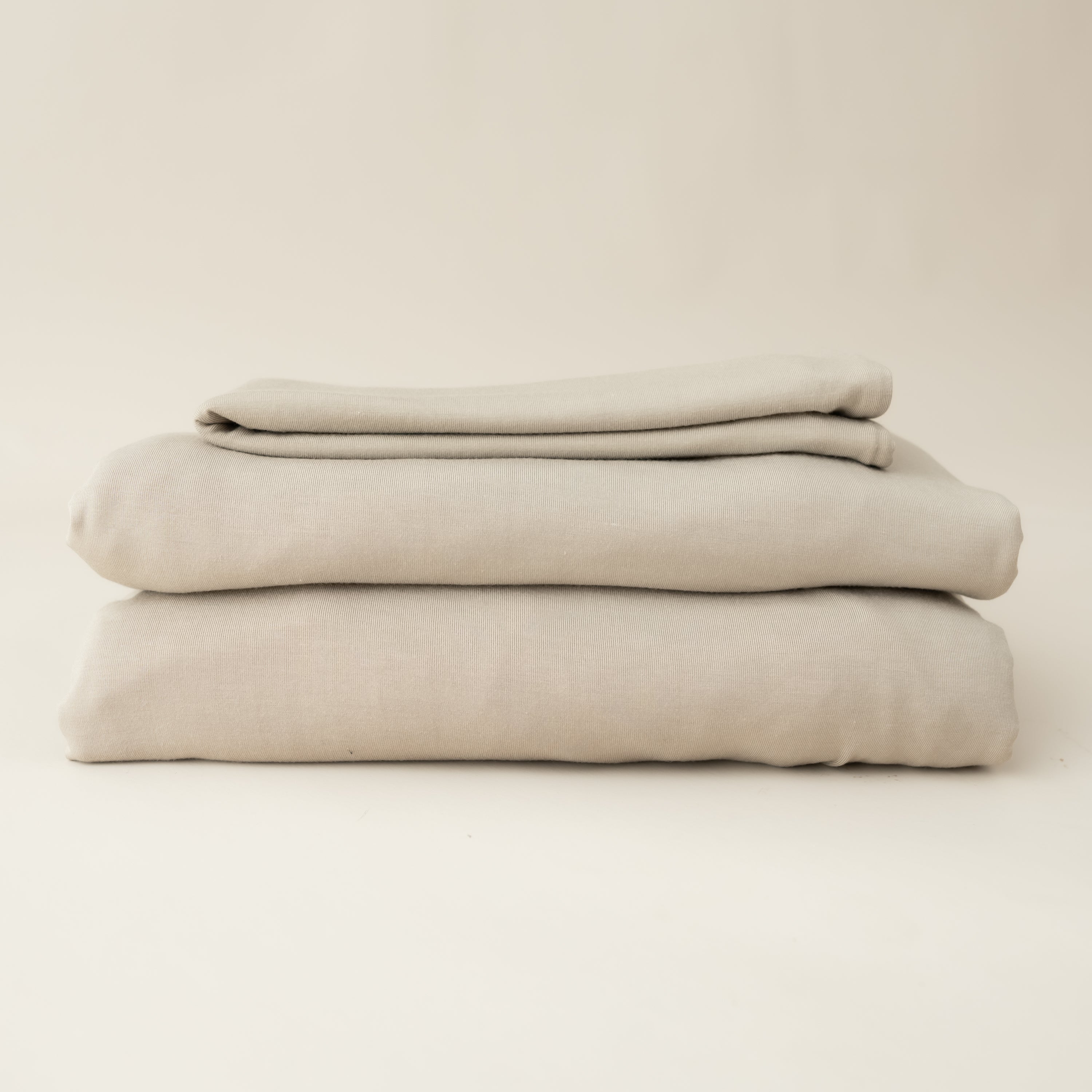 almond fitted sheet and pillow cases neatly folded and stacked on top of each other 