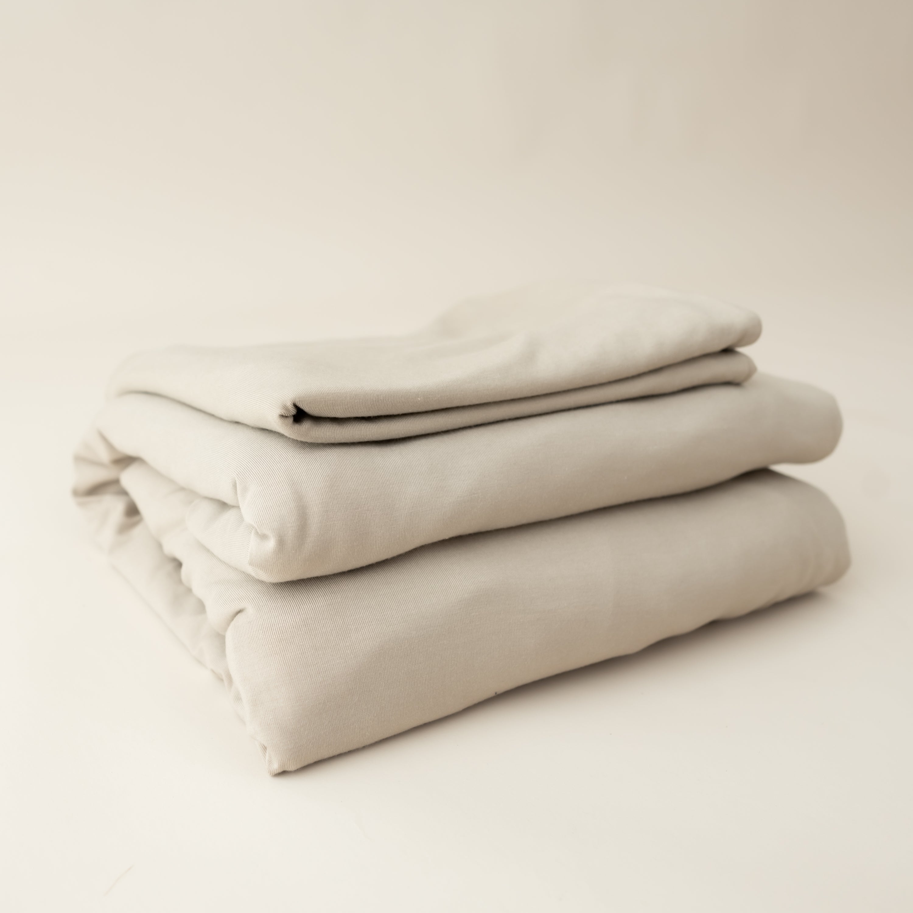 almond fitted sheet and pillow cases neatly folded and stacked on top of each other in an angle 