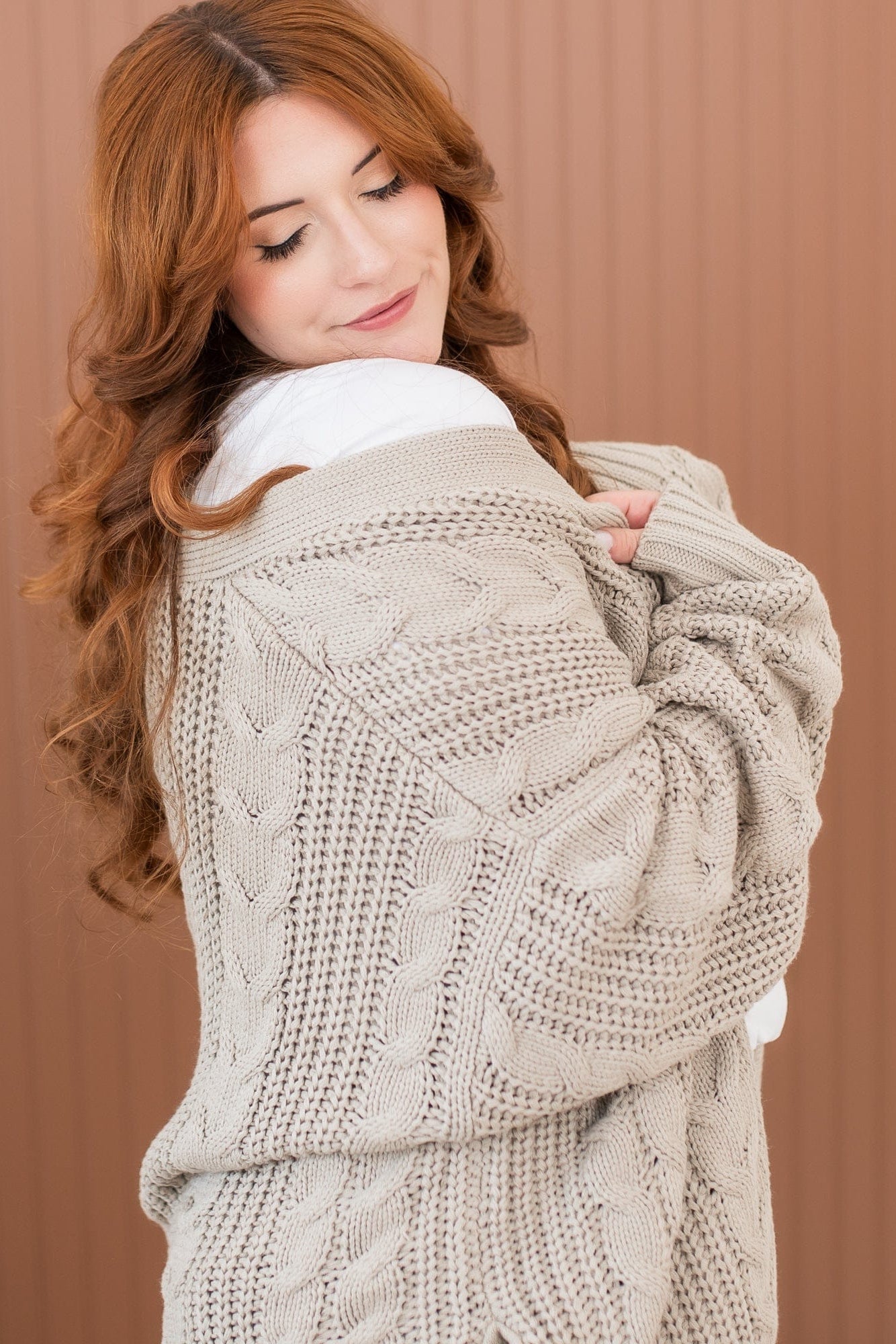 Female model wearing the Cable Knit Adult Cardigan in Almond off of her shoulder