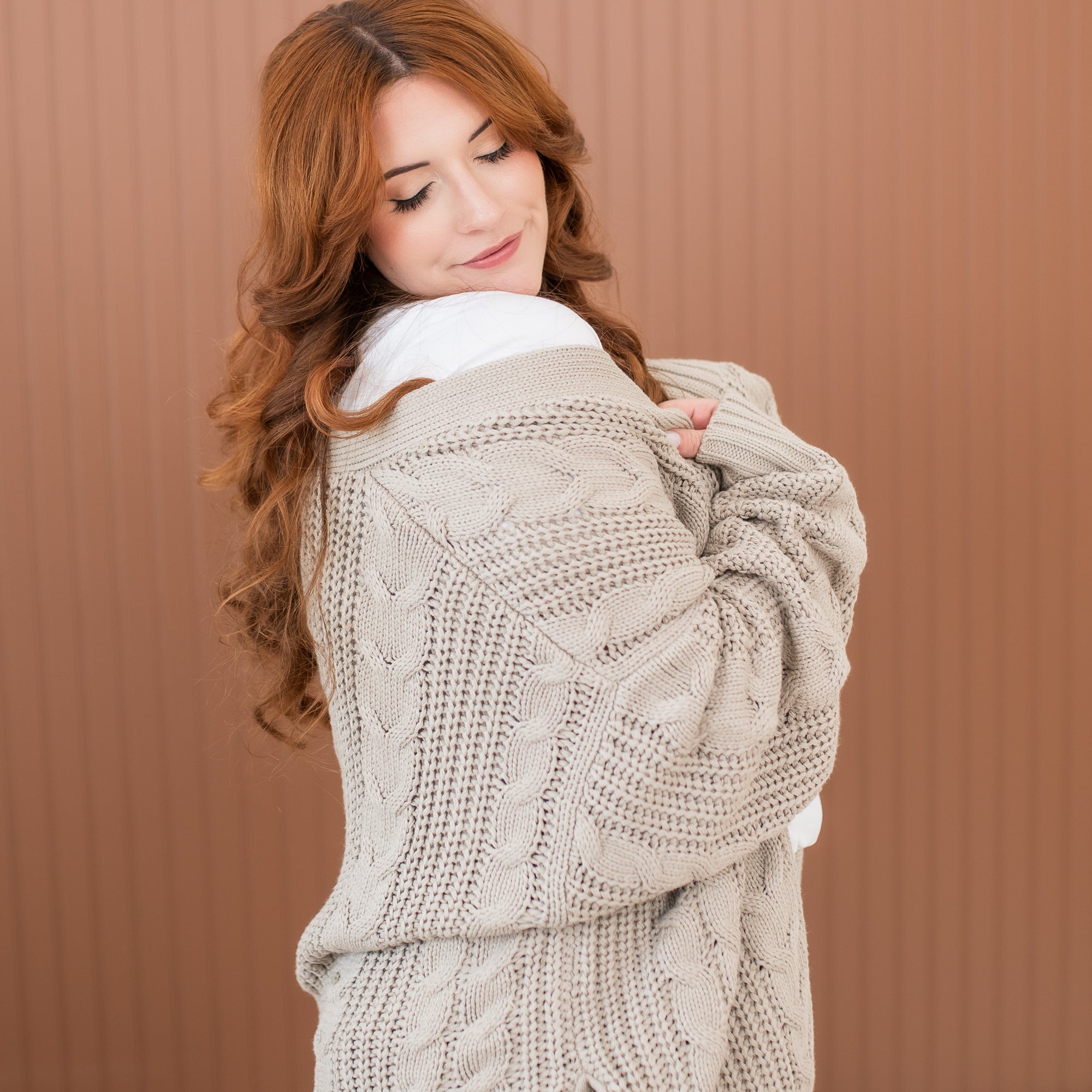 Female model wearing the Cable Knit Adult Cardigan in Almond off of her shoulder