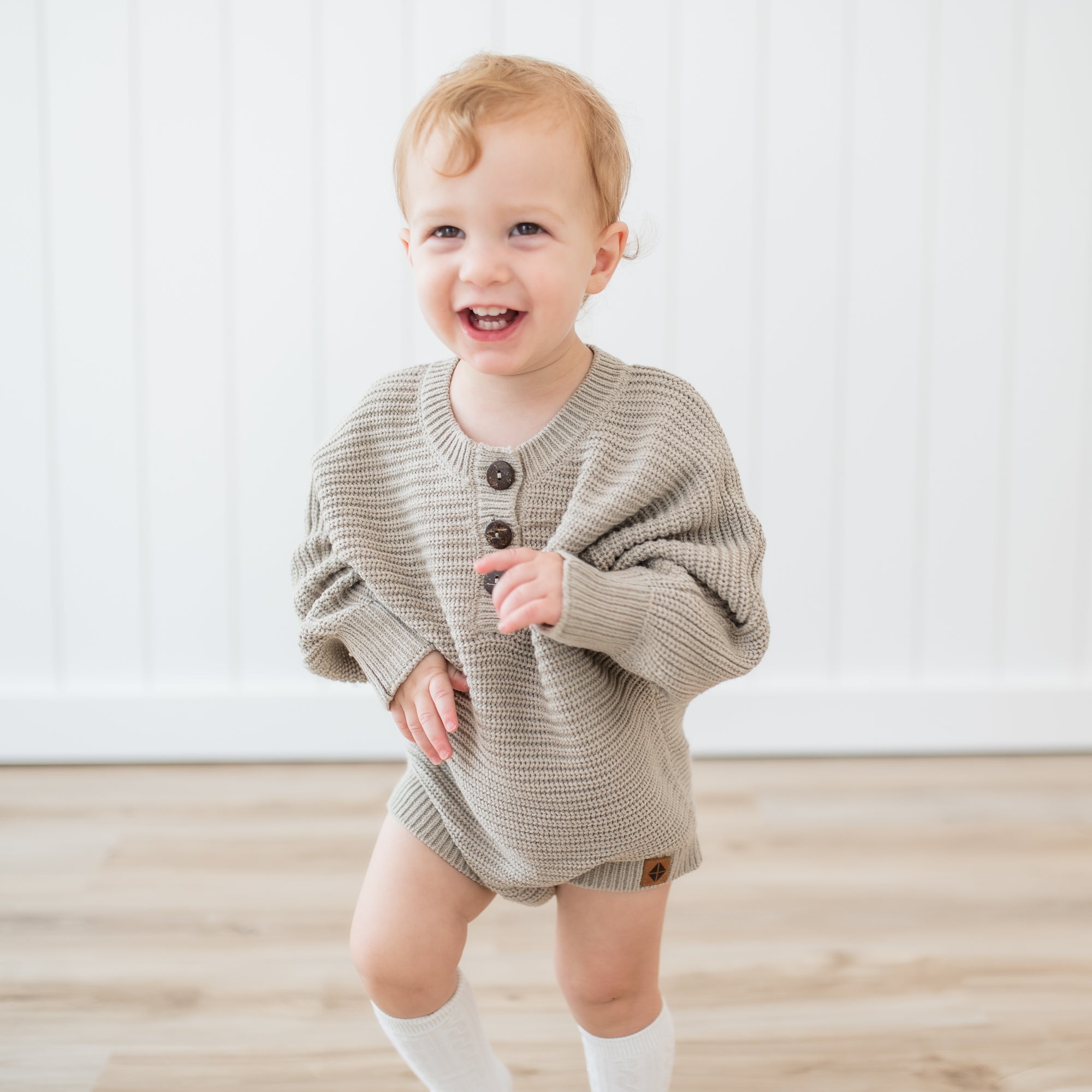 Smiling toddler wearing the Chunky Knit Romper in Almond