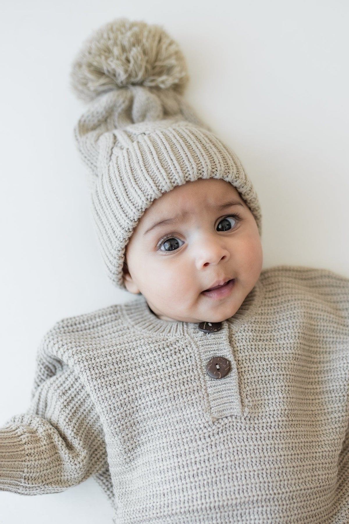 Close up of the Chunky Cable Knit Beanie in Almond shown on an infant wearing the Chunky knit romper in Almond