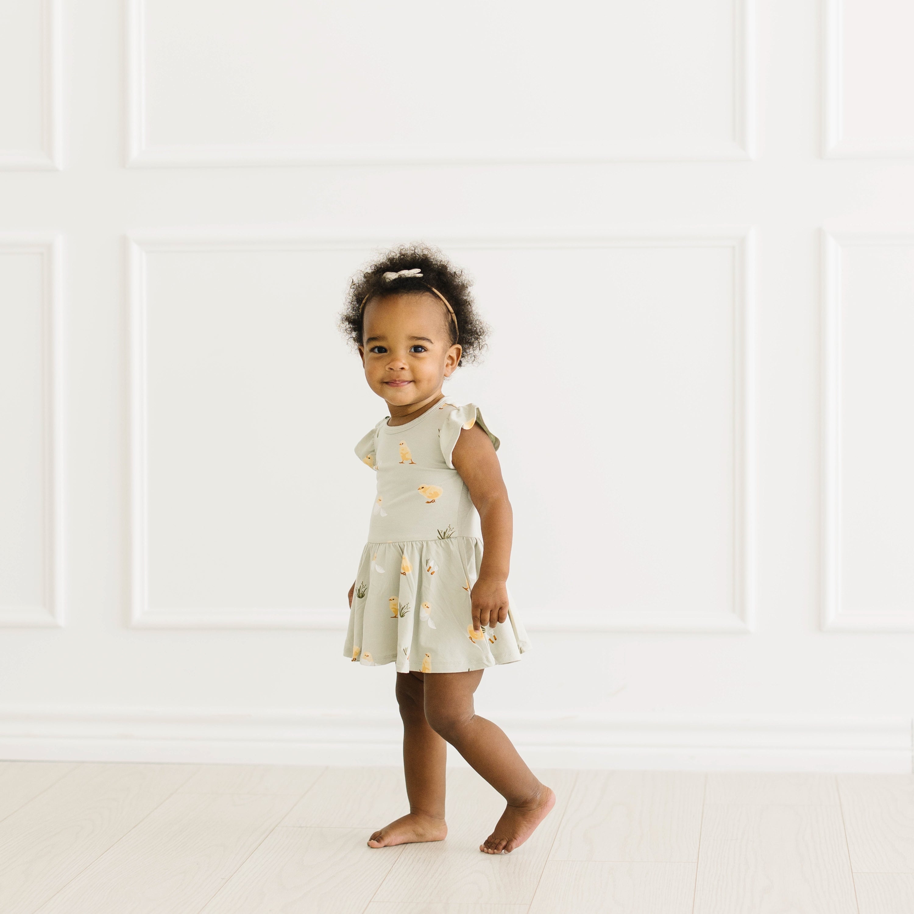 Toddler smiling in Twirl Bodysuit Dress in Aloe Chick