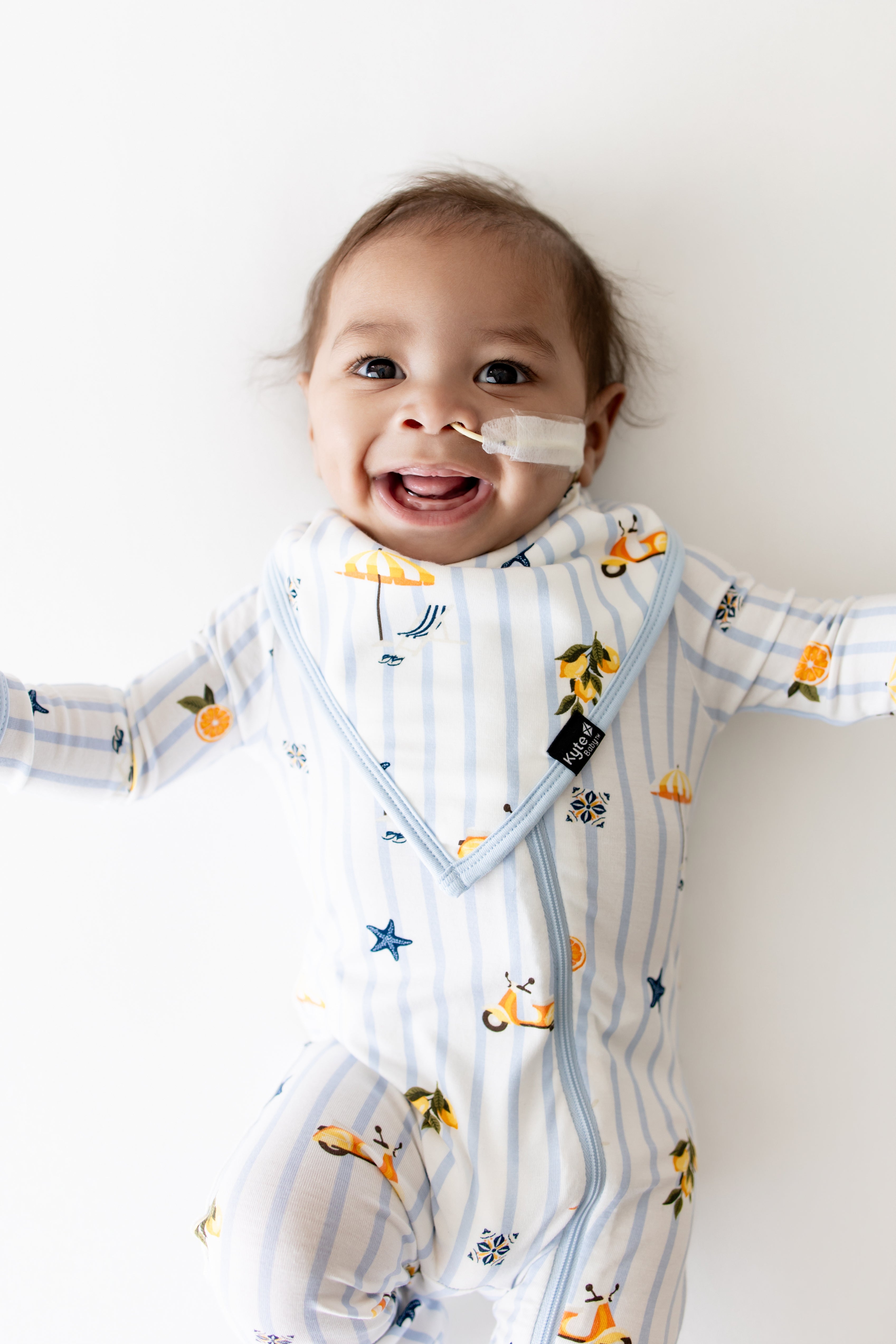 Smiling infant wearing the Bib in Amalfi Coast with the matching zipper romper