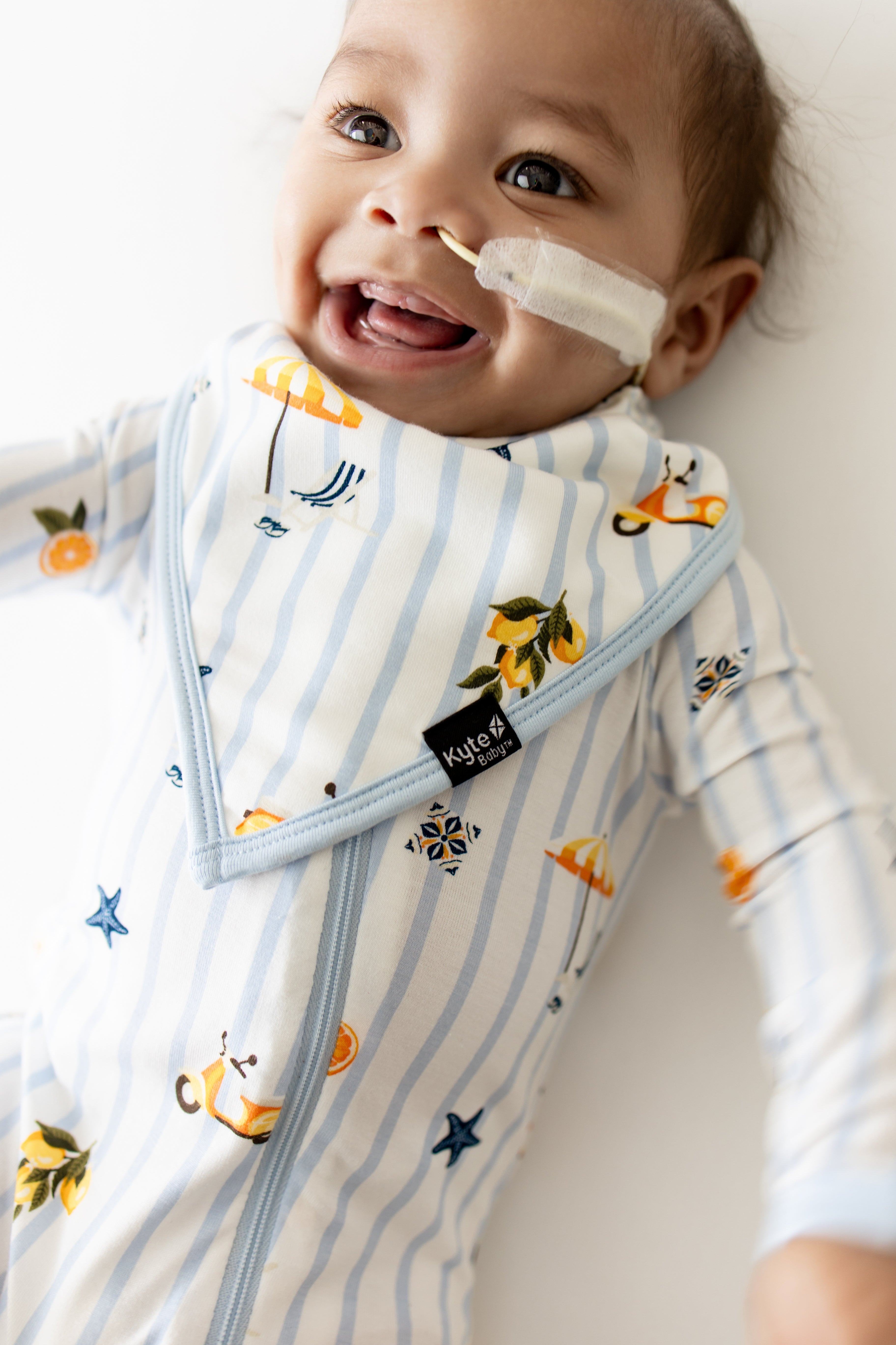 Smiling infant wearing the Bib in Amalfi Coast with matching romper on underneath