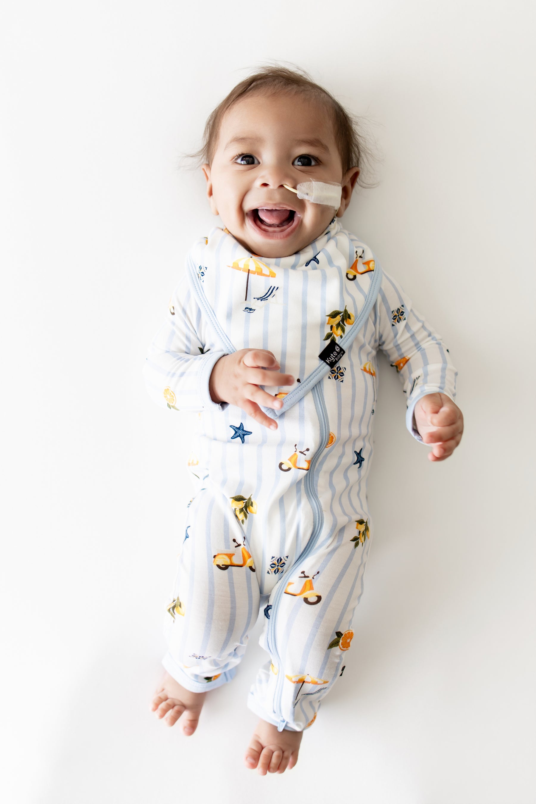 Smiling infant wearing the Bib in Amalfi Coast with the matching zippered romper